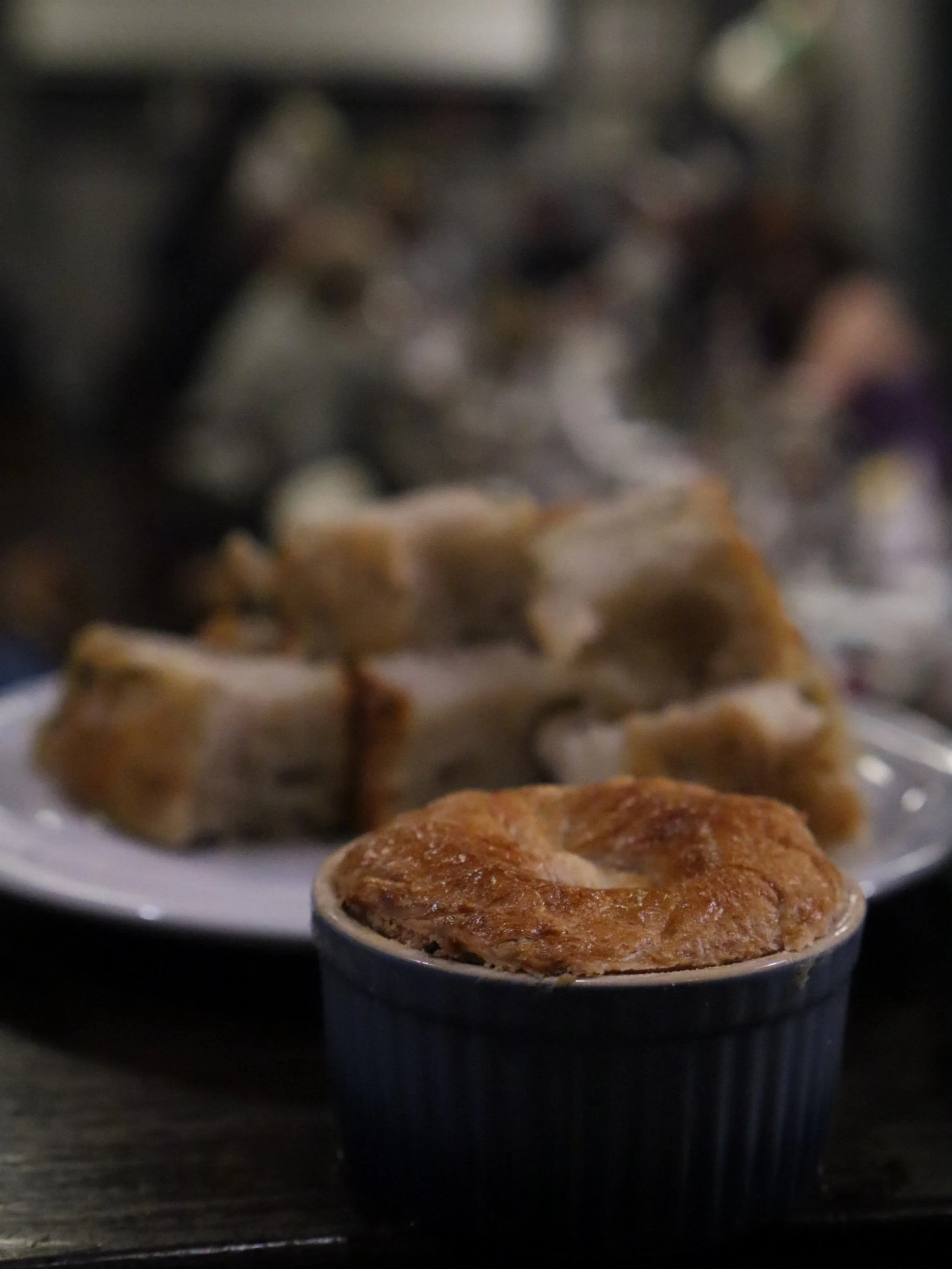 Golden puff pastry pie served in a ramekin with bread in the background.
