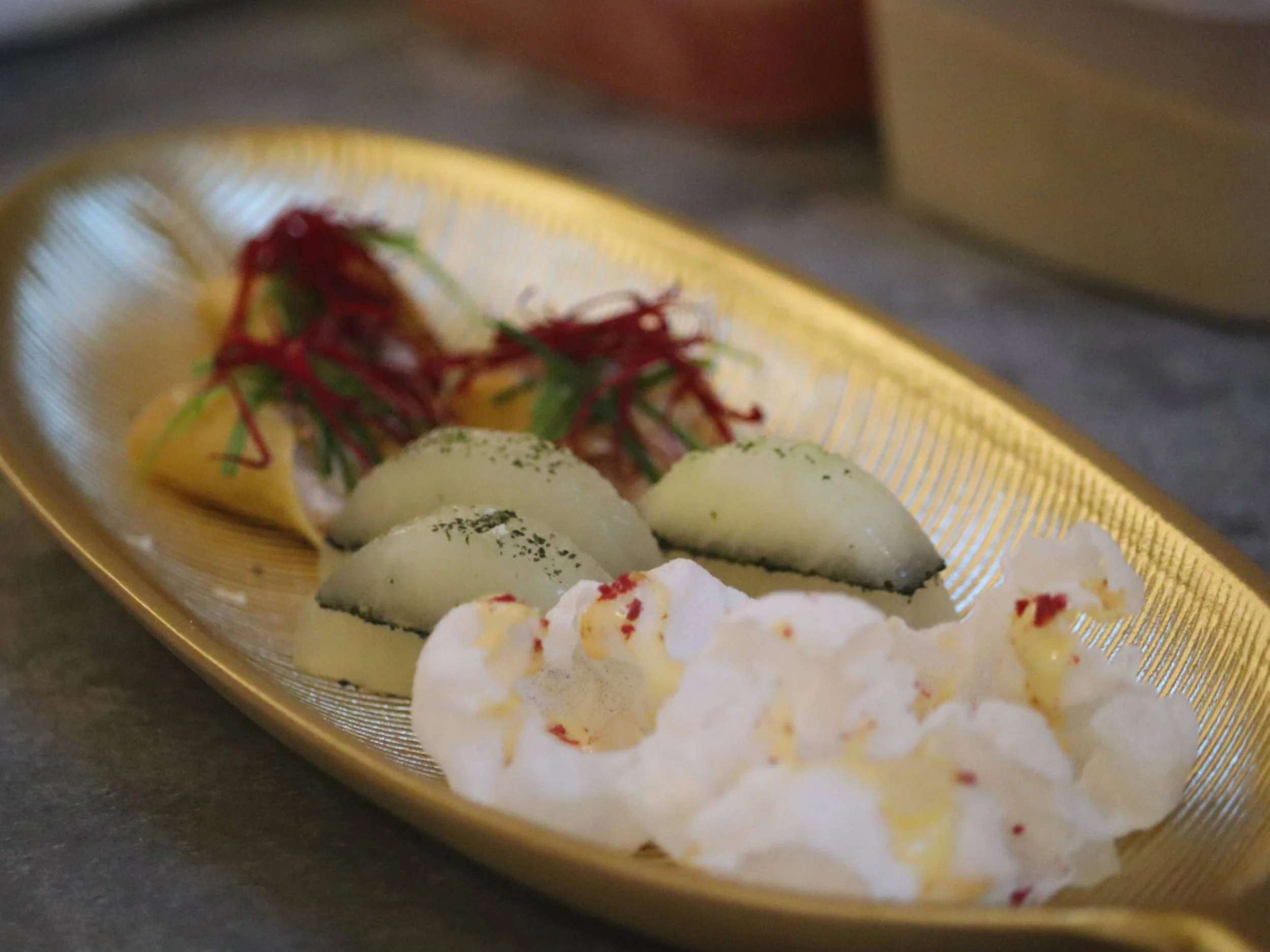Fine dining tasting platter with delicate layered bites, crisp garnishes and red micro-herbs.