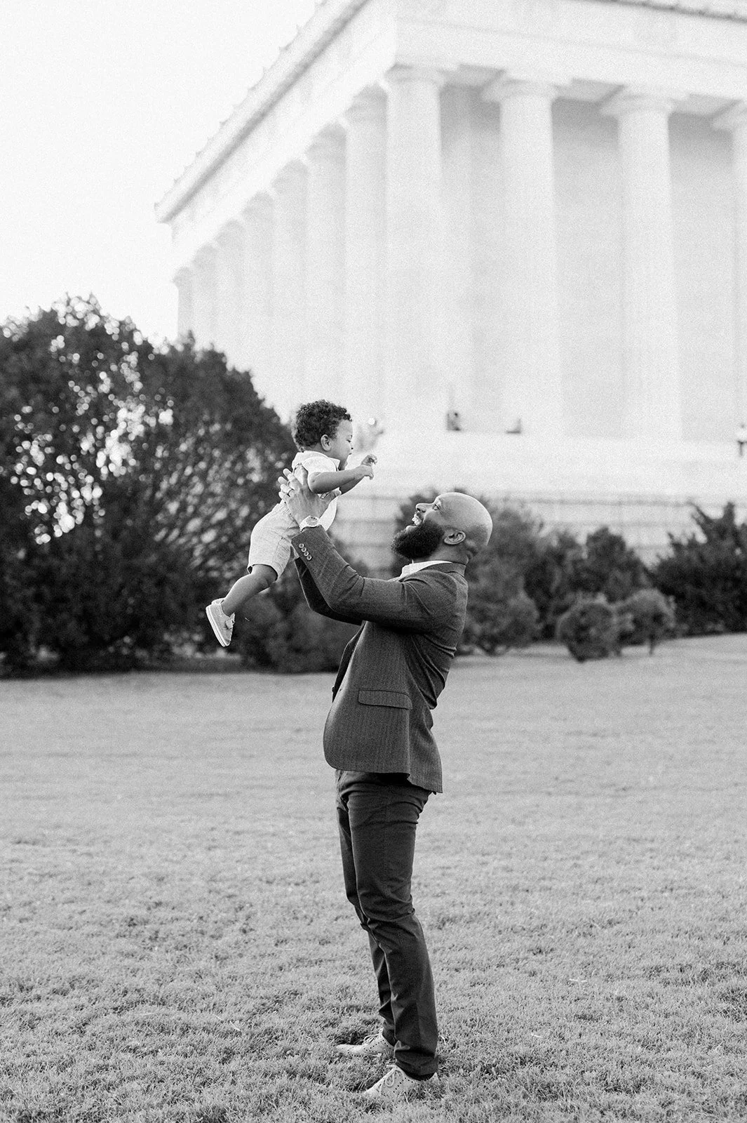A father holding his toddler in the air.