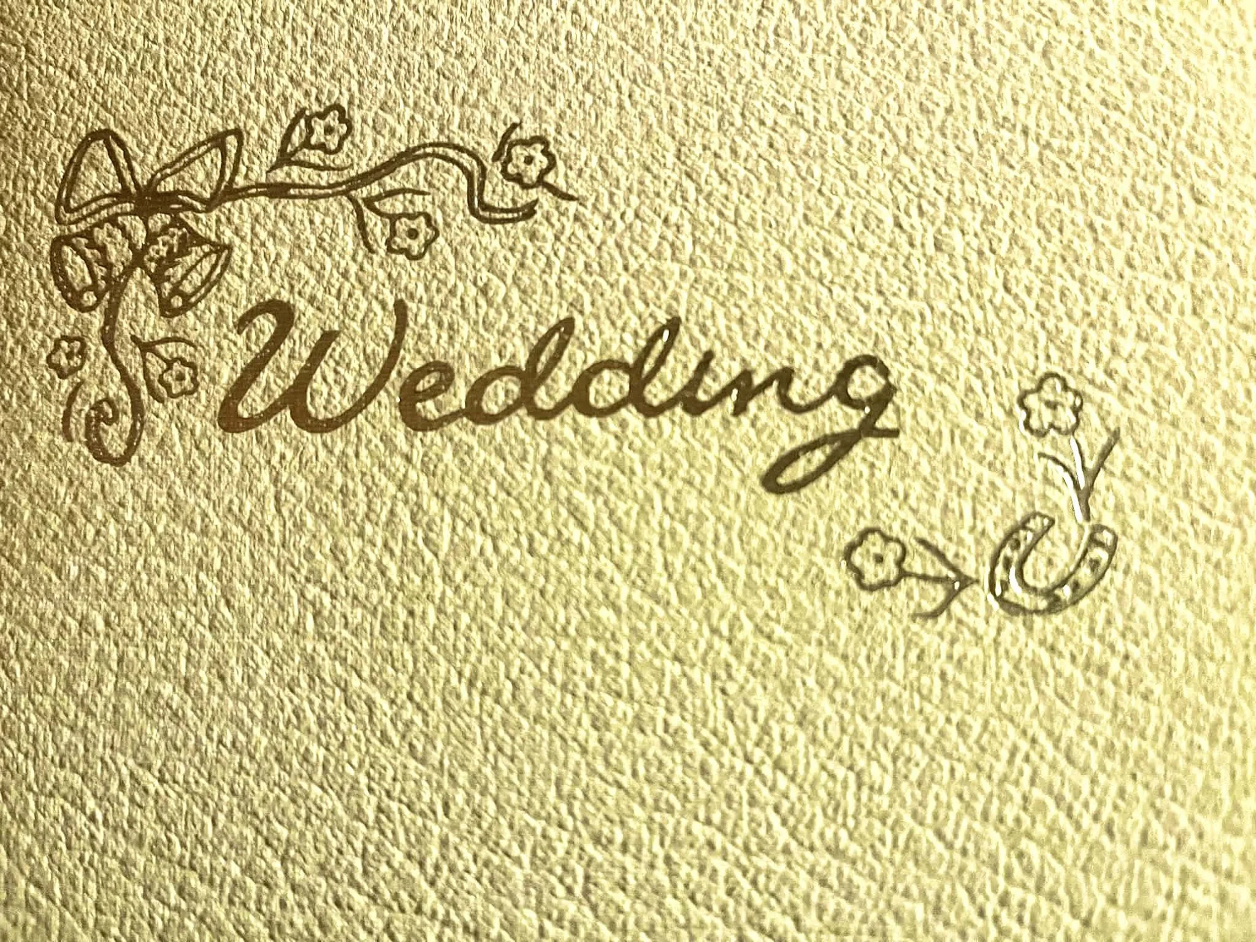 Gold-colored textured background with the word "Wedding" and decorative floral illustrations.