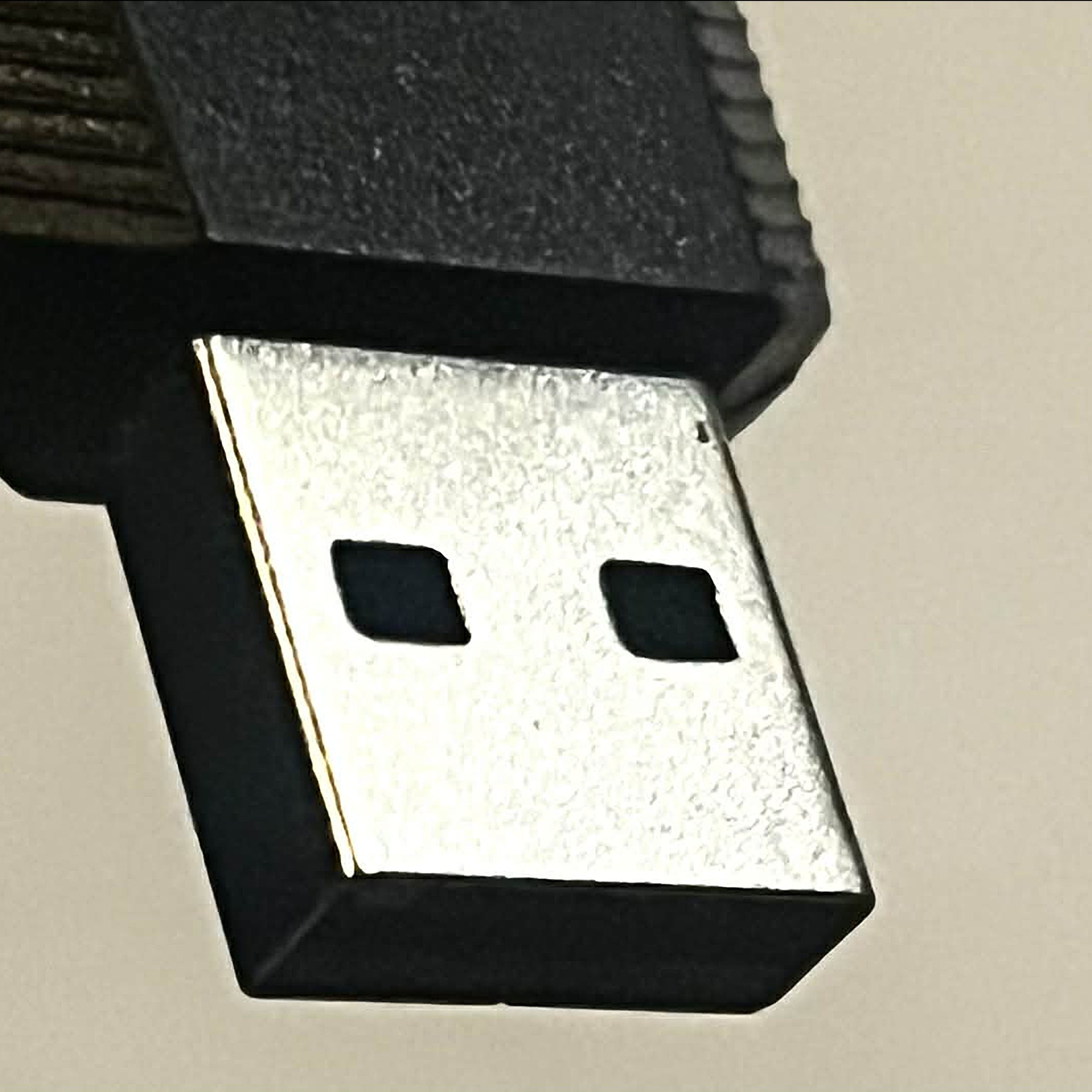 Close-up of a USB plug with a black casing and metallic connectors, partially inserted into a black socket or device.