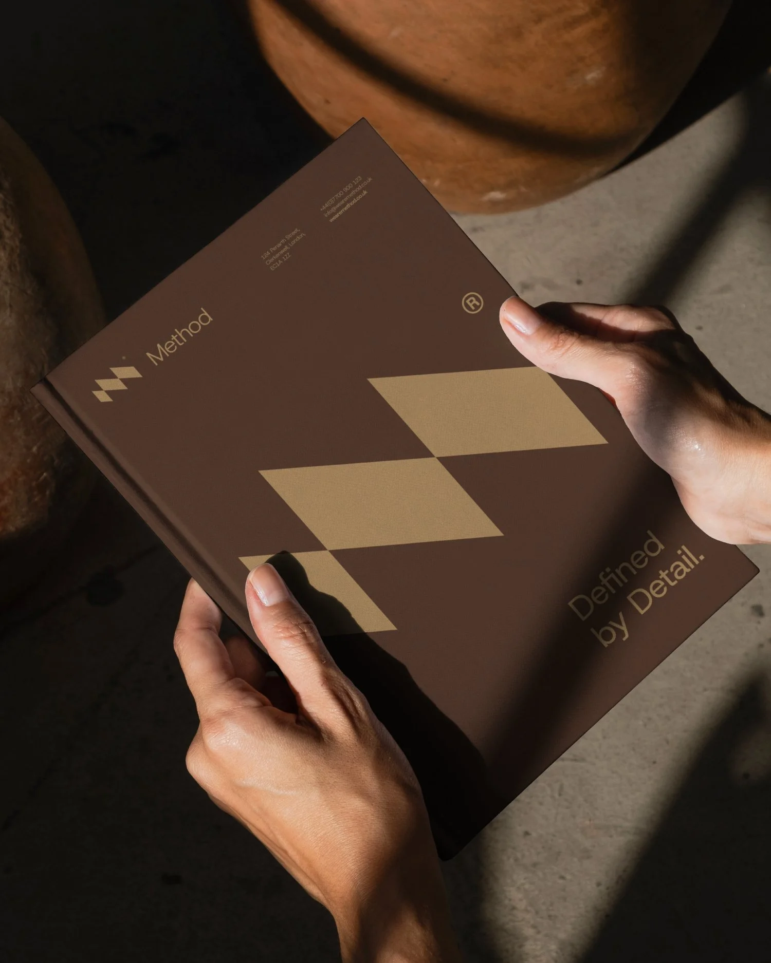 Person holding a brown box with 'Method' written on it, the box has beige geometric shapes and the wording ‘Designed by Detail’.