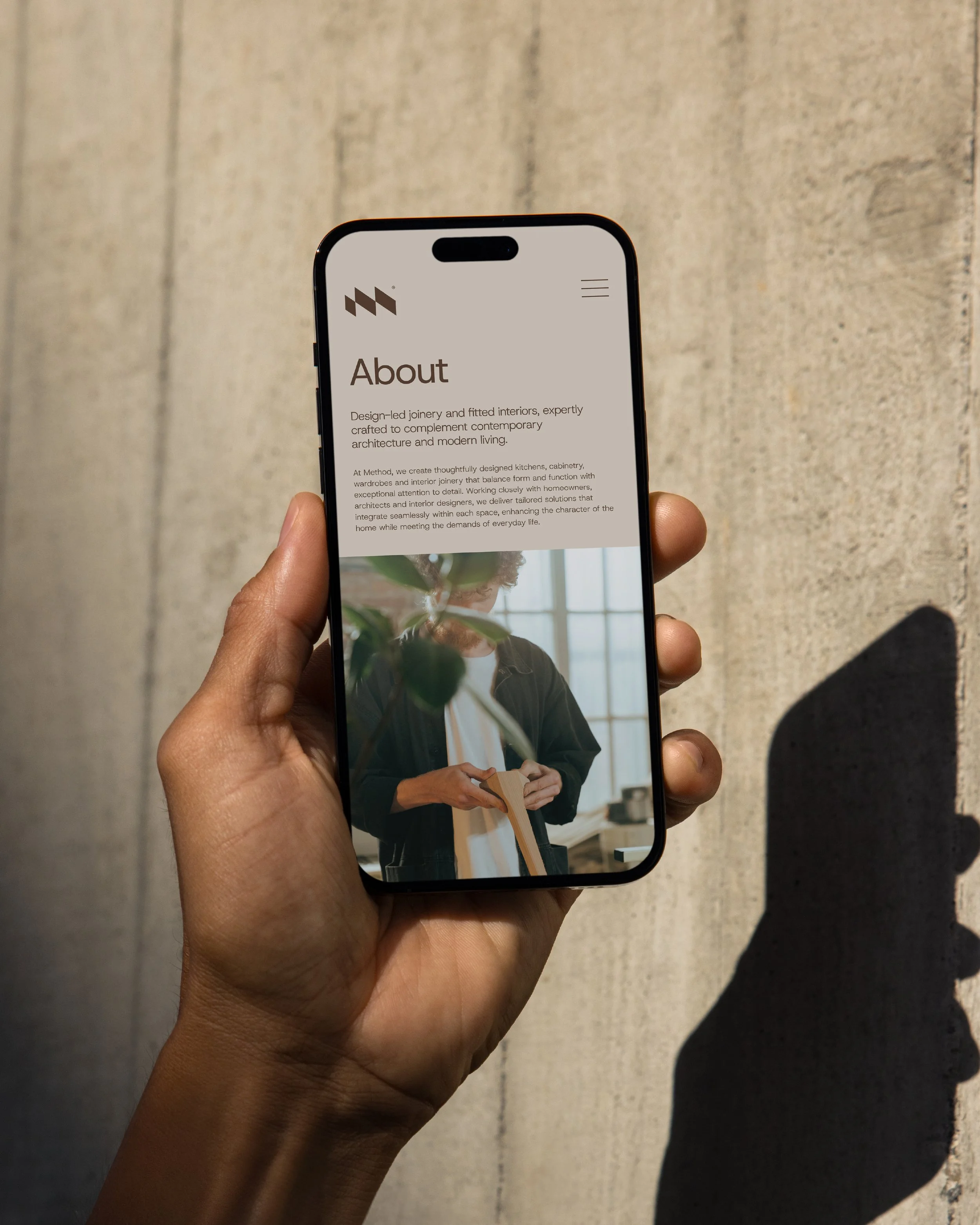 Close-up of a person holding a smartphone displaying a webpage about interior design.