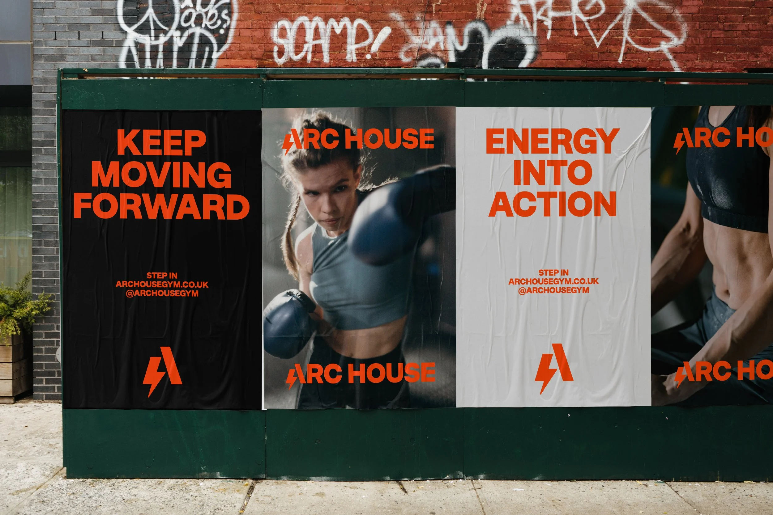 Advertising poster on a green outdoor wall promoting a gym called Arc House, featuring a woman in athletic pose and wearing workout clothes, with large bold orange text saying 'Keep Moving Forward' and 'Energy Into Action', alongside the gym's website and social media handle.