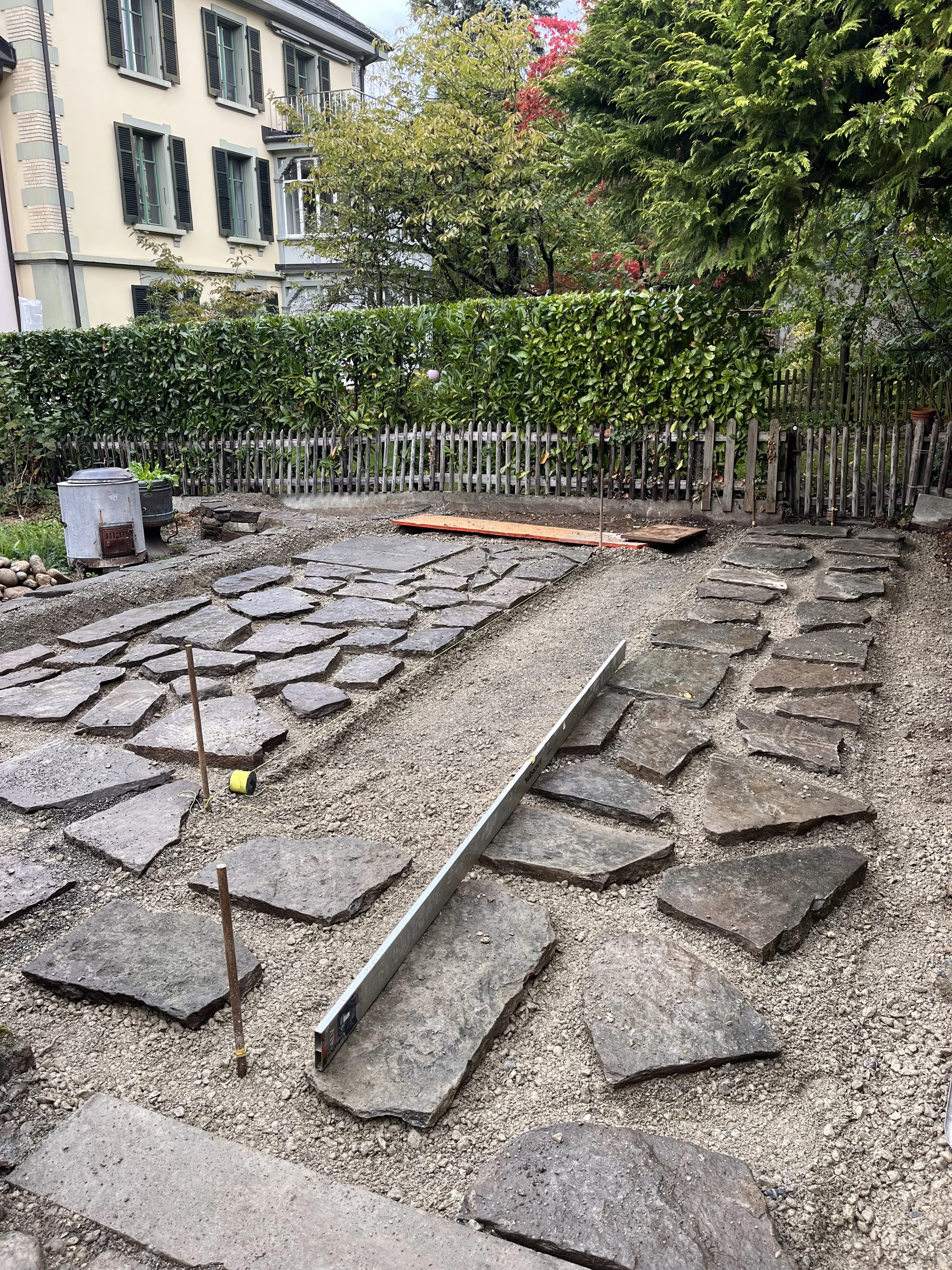 Neu verlegte Natursteinplatten im offenen Fugenbild als Aufenthaltsbereich im Garten