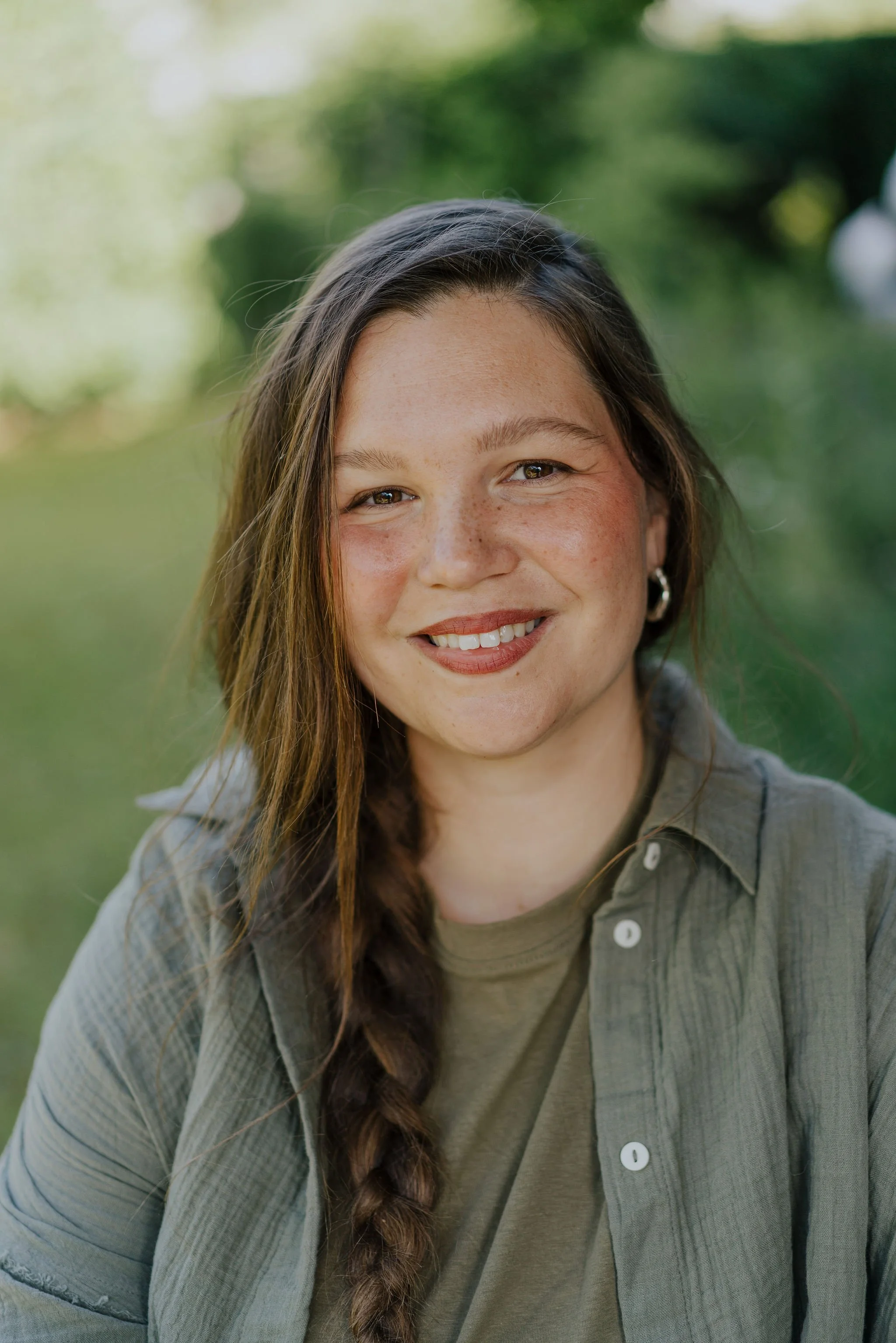 Portrait von Naomie in einem naturnahen Garten mit Pflanzen im Hintergrund