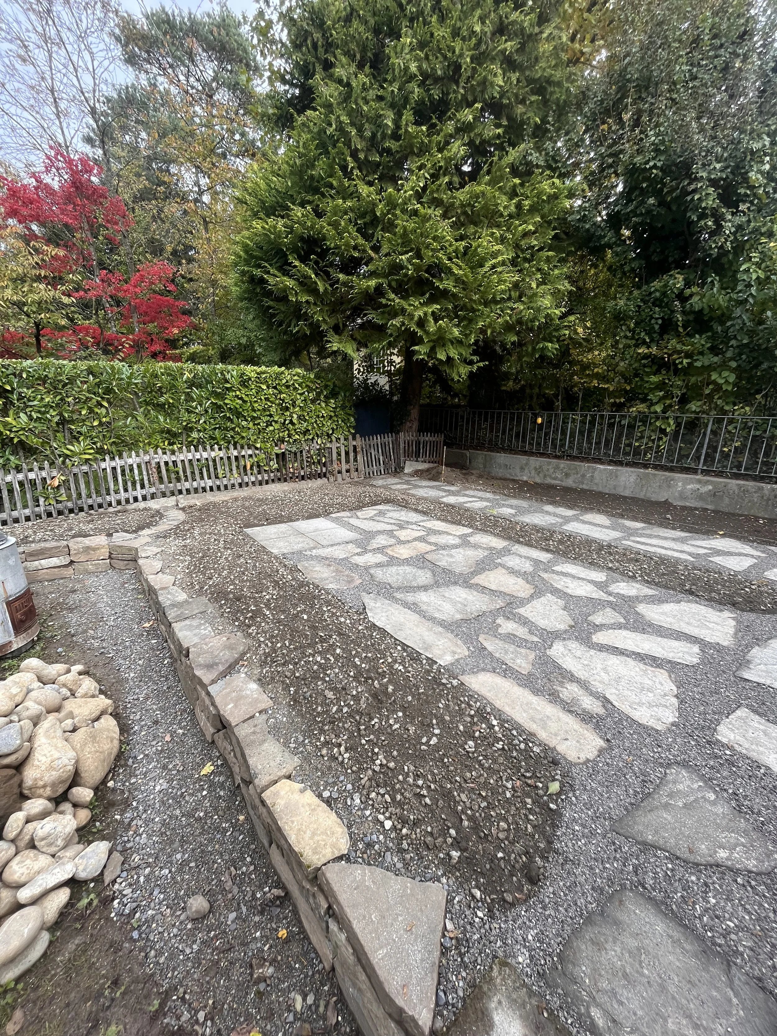 Anlage eines Natursteinplatzes mit recycelten Platten und strukturierten Ebenen im Recycling-Garten Kirchfeld Bern