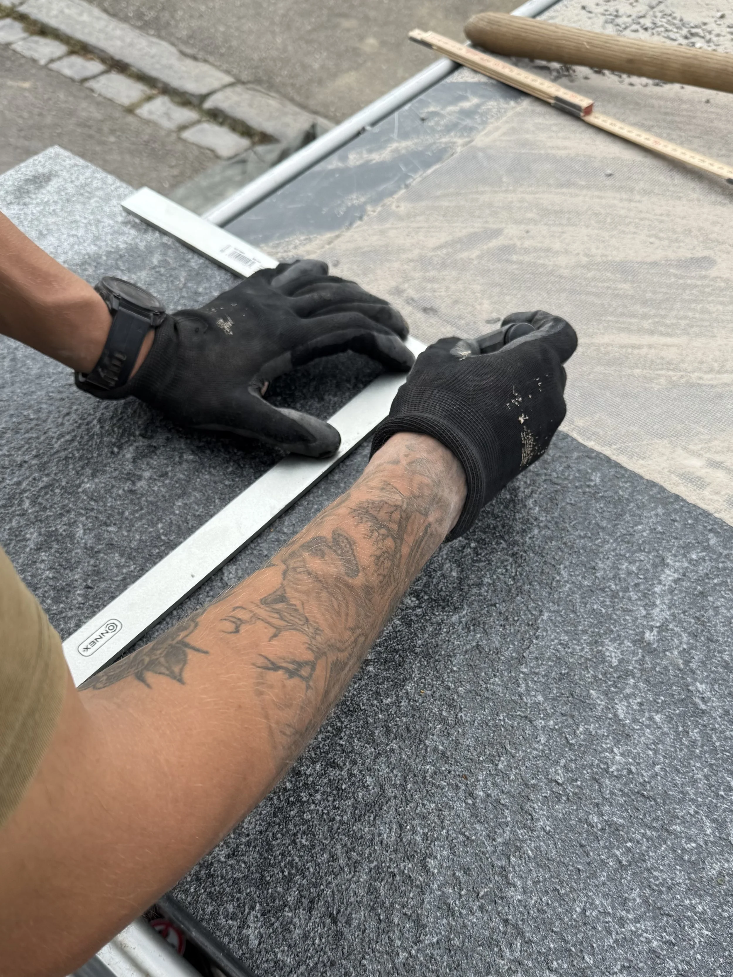 Handwerker zeichnet auf einer Natursteinplatte