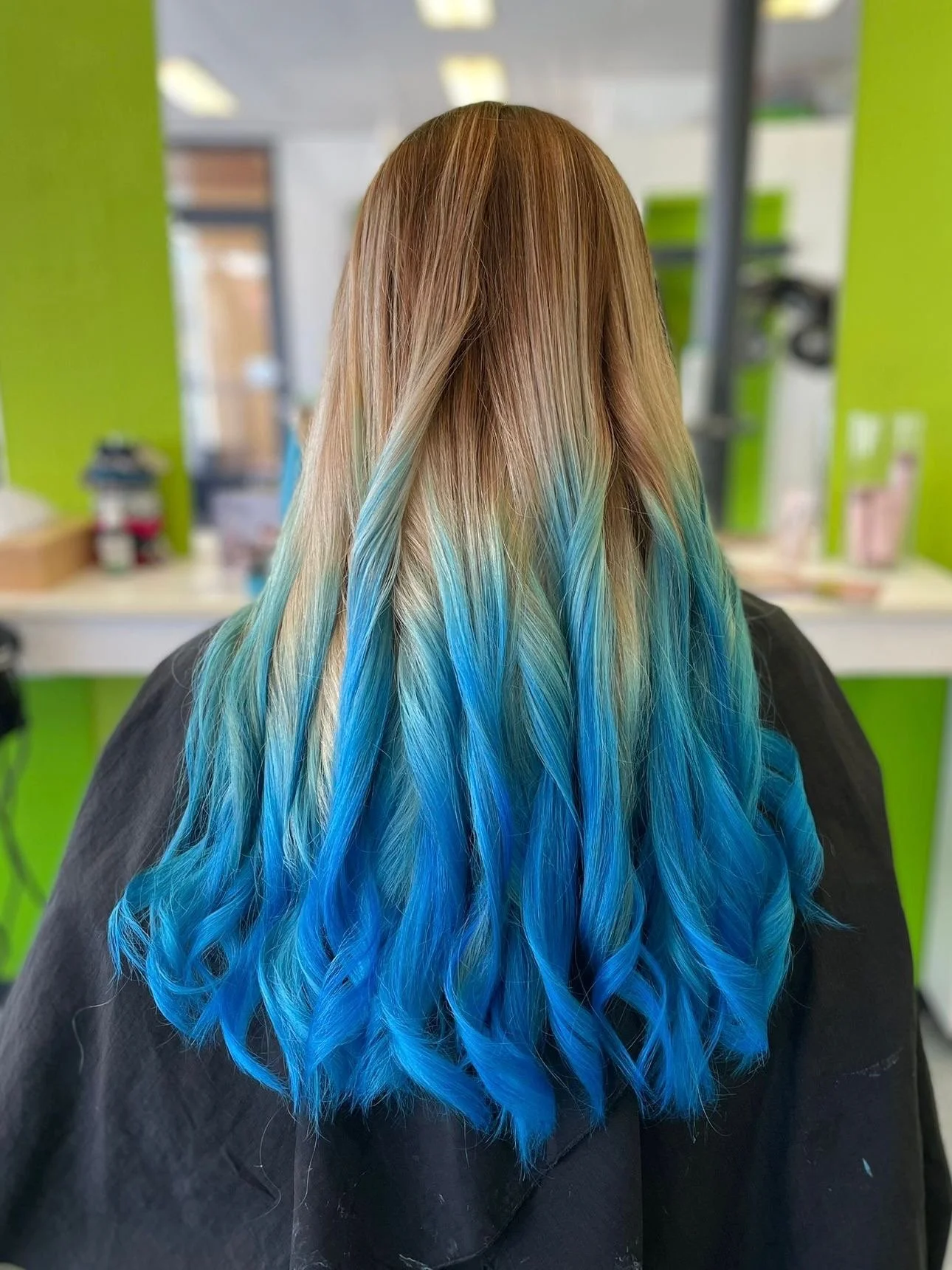 Lange Haare mit blonden Ansätzen und blau gefärbten Spitzen in einem Frisörsalon.