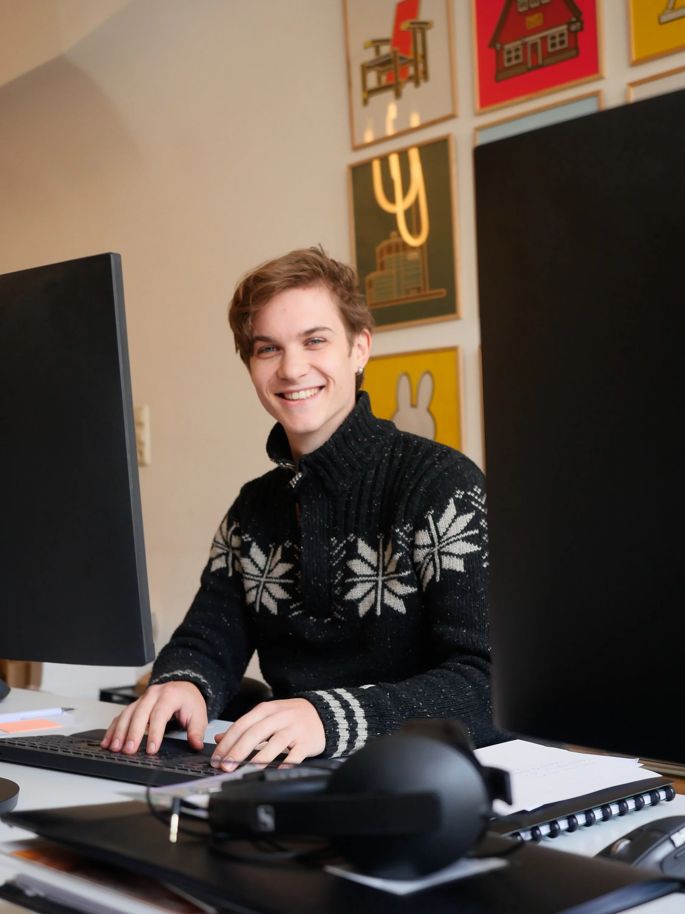 Jongeman die aan een bureau zit te editen met een computer, lachend.