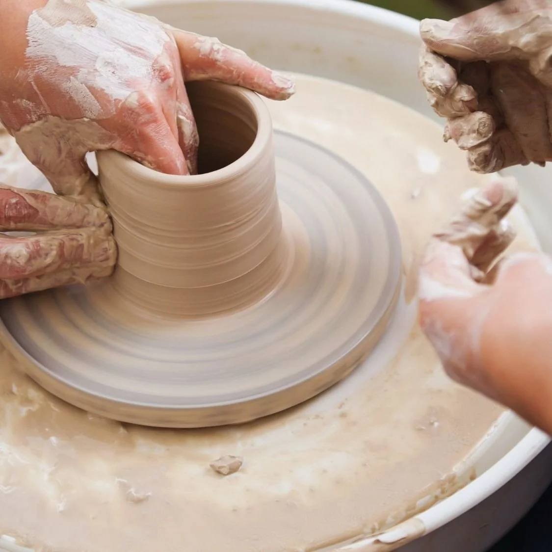 Hands carefully shaping clay on a pottery wheel