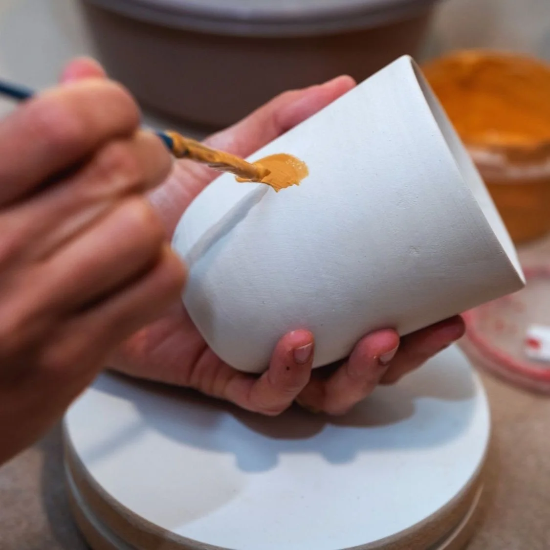 Hands painting a piece of pottery