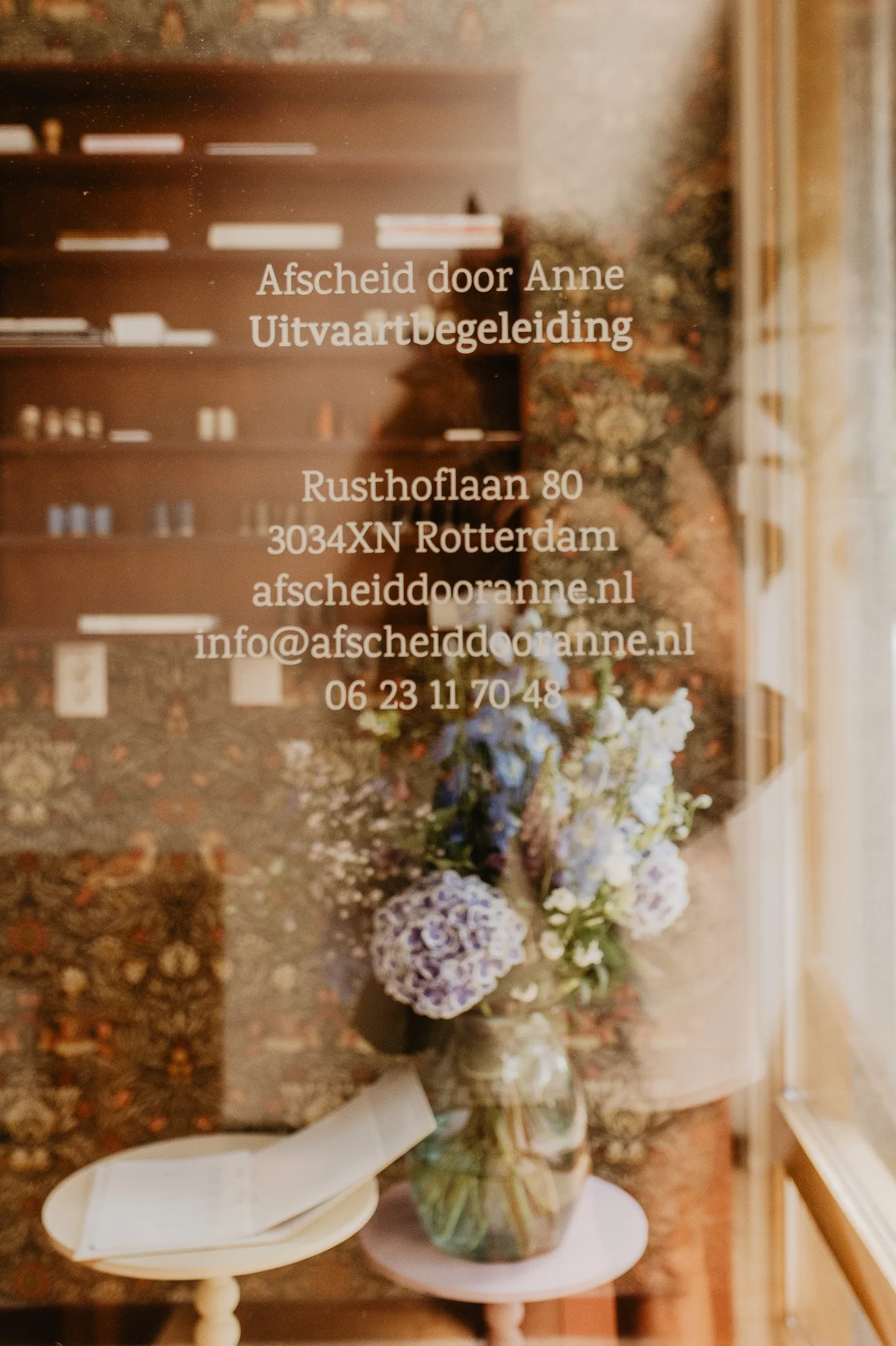 Adres, emailadres en telefoonnummer van Afscheid door Anne gedrukt op de ruit van de voordeur van het kantoor in Kralingen-Crooswijk.