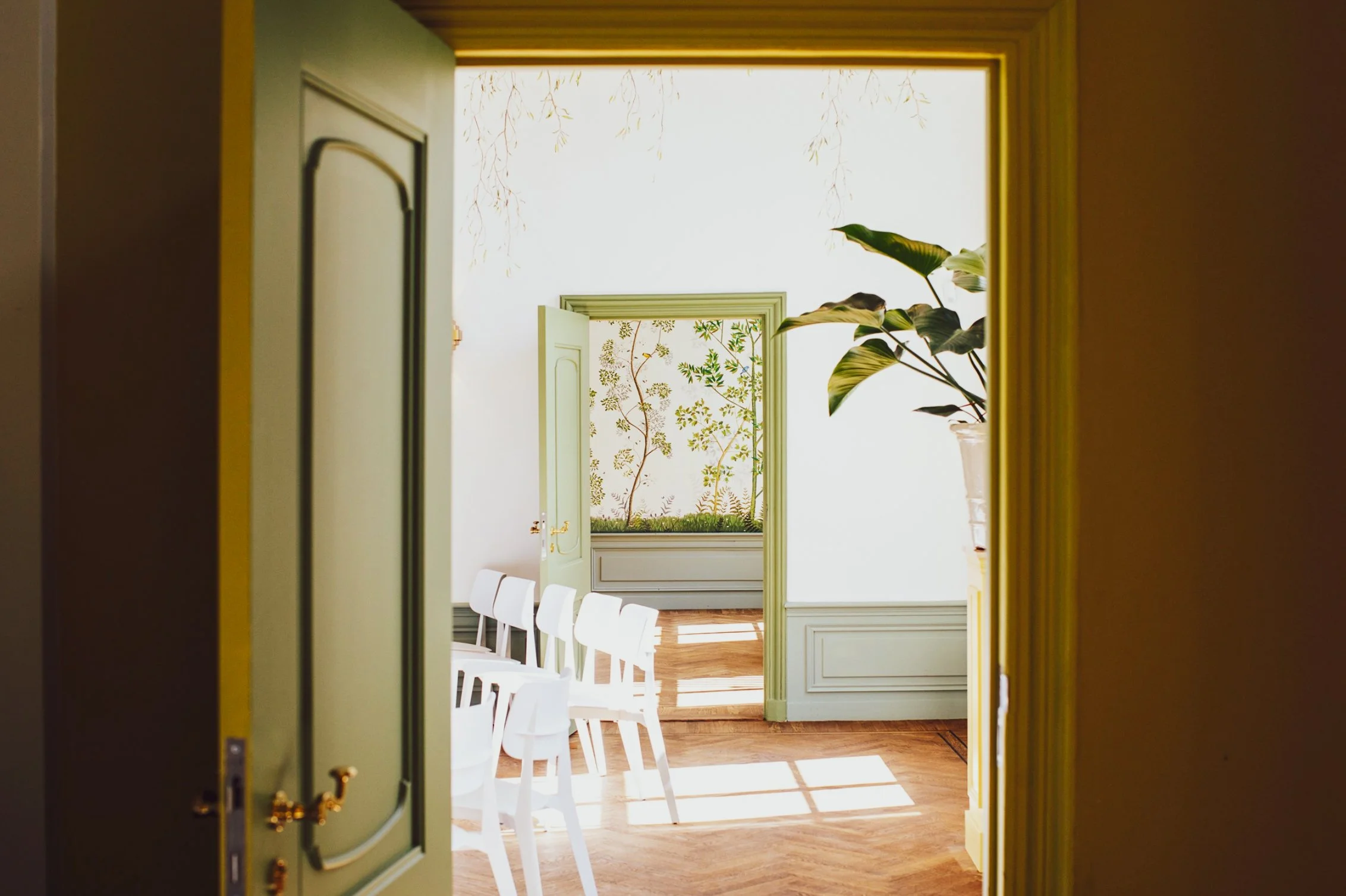 Interieur uitvaartlocatie Dudok in het Park in Rotterdam. Op de foto is het interieur te zien met een houten vloer en witte stoelen.