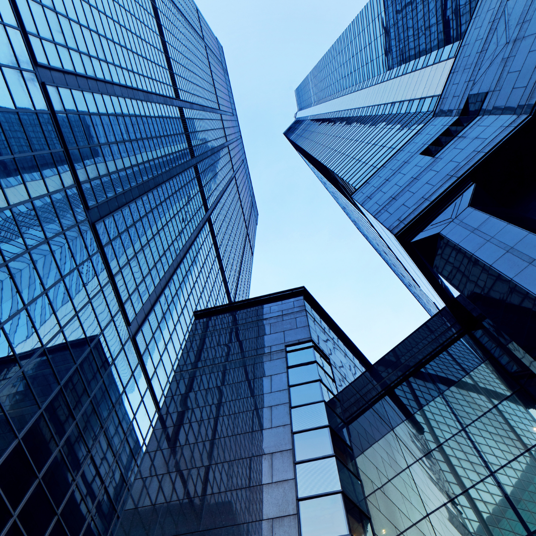 Edificios de oficinas de vidrio altos vistos desde abajo mirando hacia el cielo.