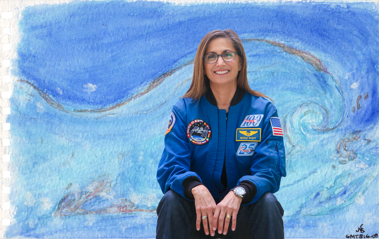 A woman in a blue NASA astronaut jacket sitting in front of a colorful, watercolor painting of a swirling storm in the sky.