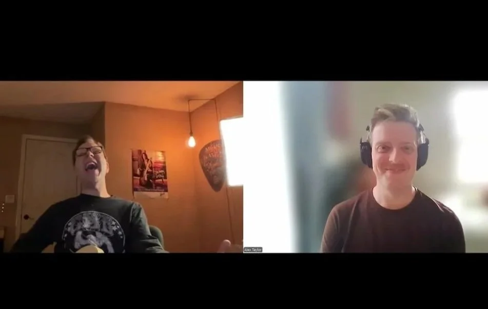 Two people on a video call, smiling and laughing. The person on the left is wearing glasses and a black t-shirt. The person on the right is wearing headphones and a dark shirt.