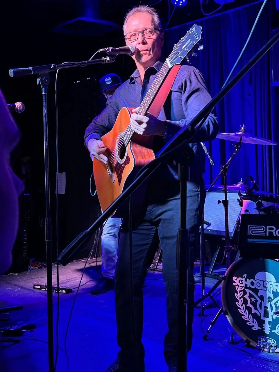 A man playing an acoustic guitar on stage during a live music performance.