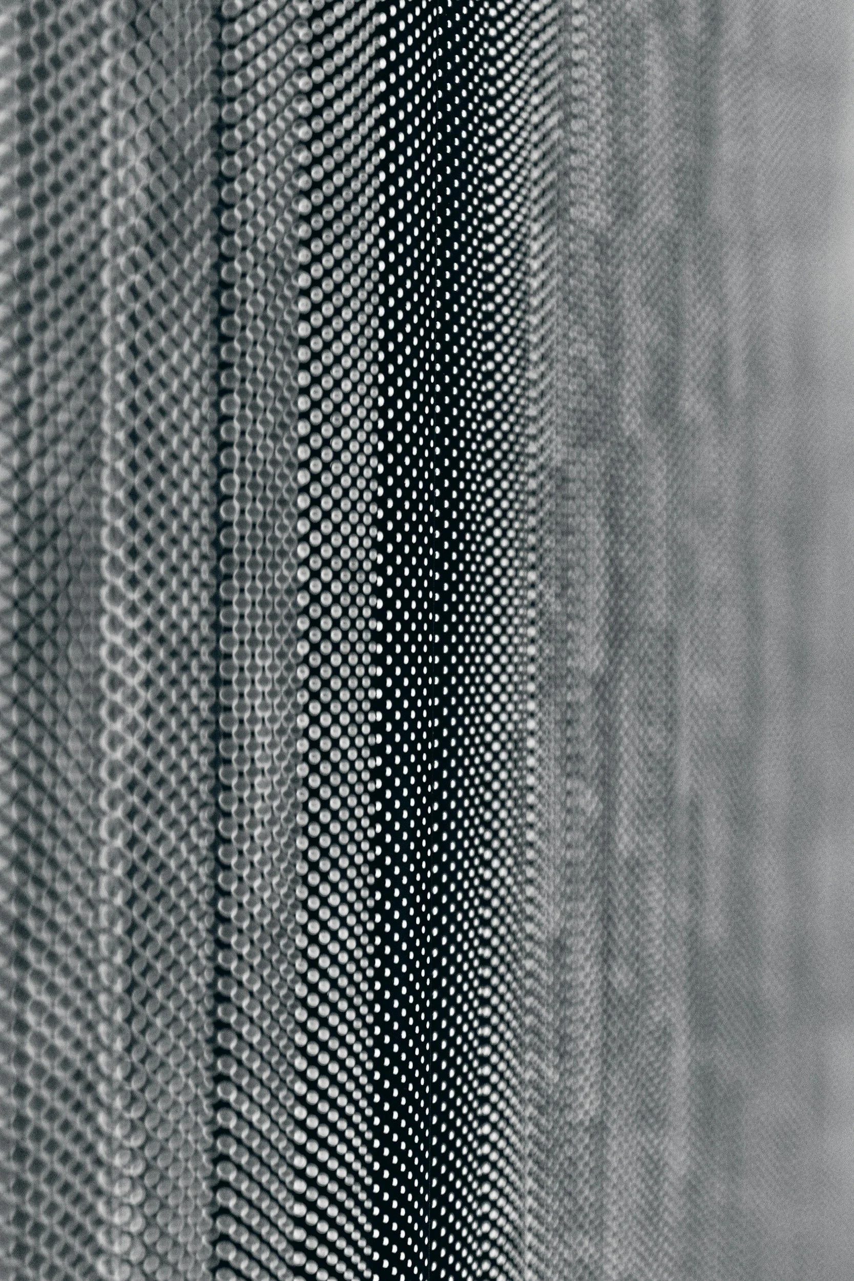 Textura de una superficie metálica con patrón de círculos pequeños en tonos grises y negros.