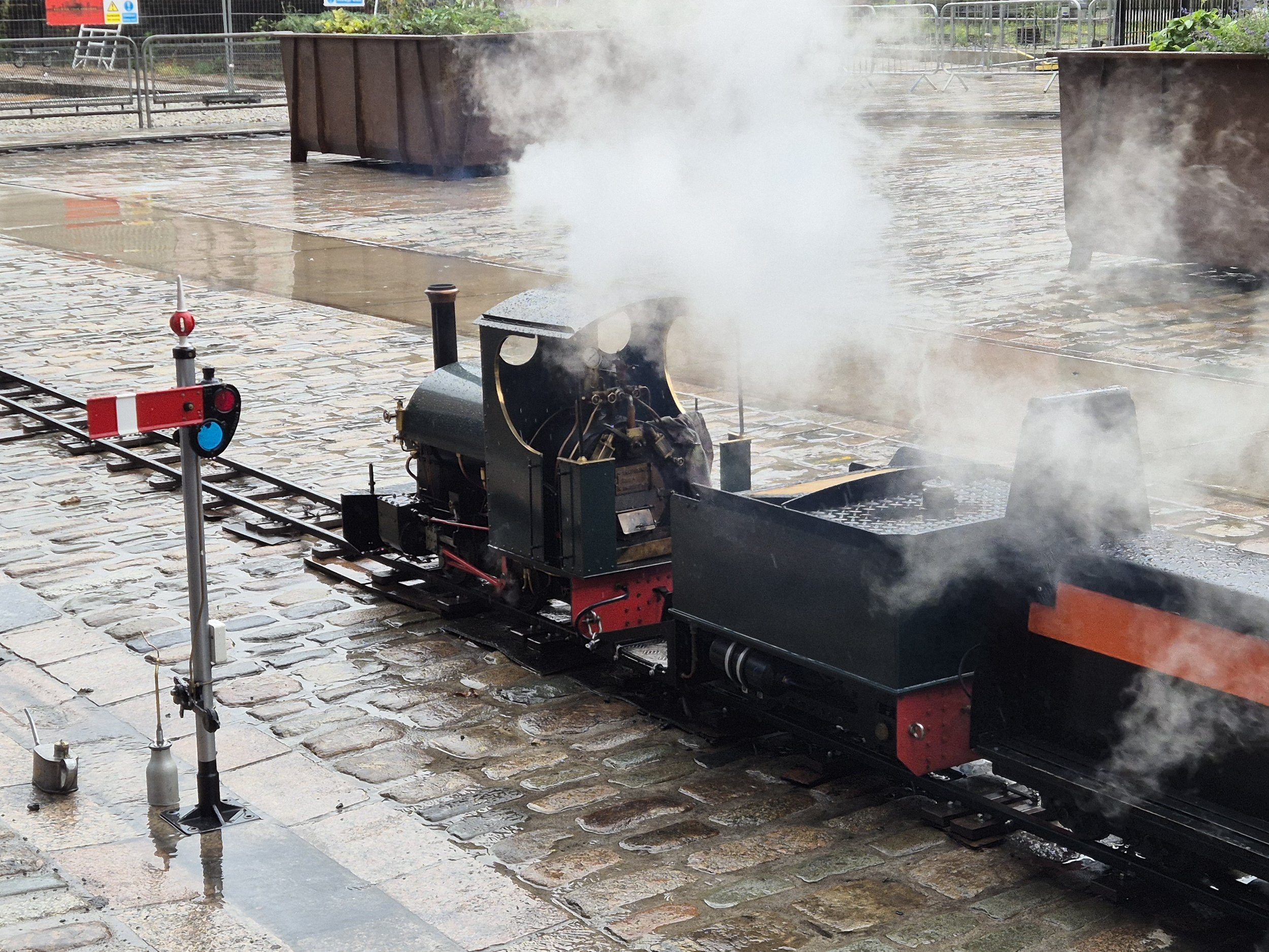 Miniature train at a Manchester Museum of Science and Industry on a wet rainy day with smoke drifting from its chimney