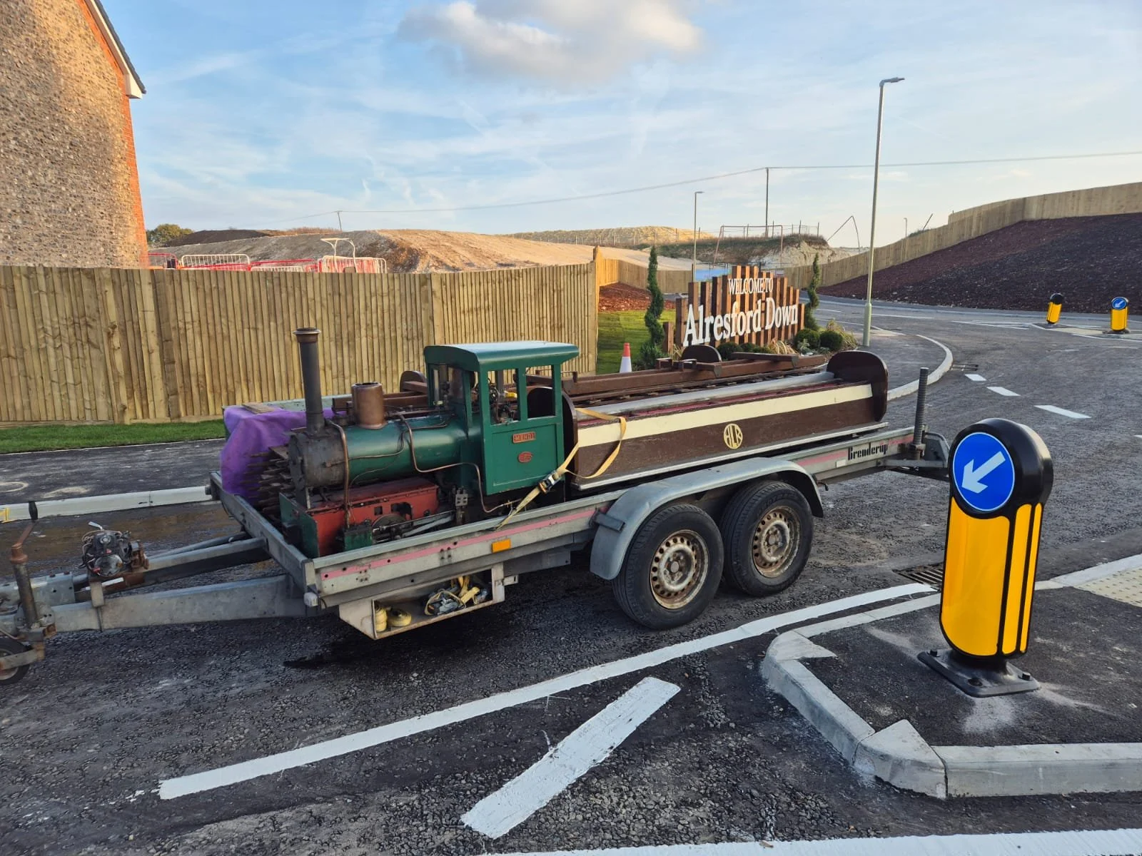 Vintage steam locomotive and carriages, loaded on a dual axle trailer pictured on a bitumen road, with a wooden fence behind, able to travel anywhere in the UK including the Midlands, Wales, North England, Lancashire, Yorkshire and Lincolnshire