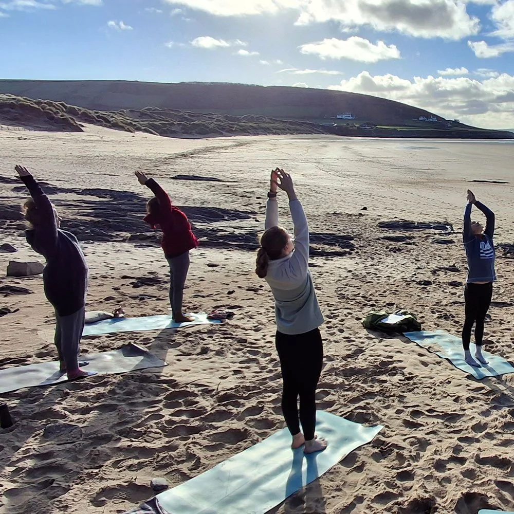 Explorers Club practicing yoga on the beach
