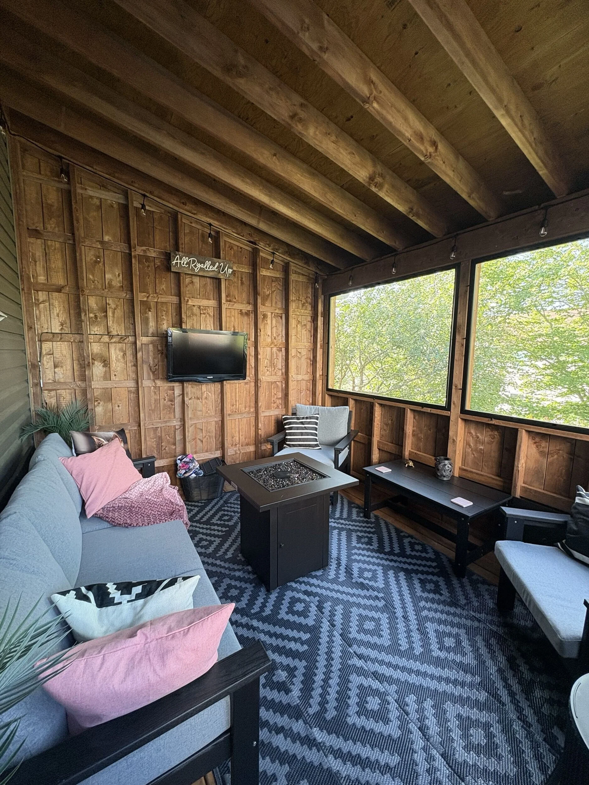 Interior of The Treehouse featuring natural wood finishes, screened openings, and comfortable seating for year-round outdoor living and entertaining.