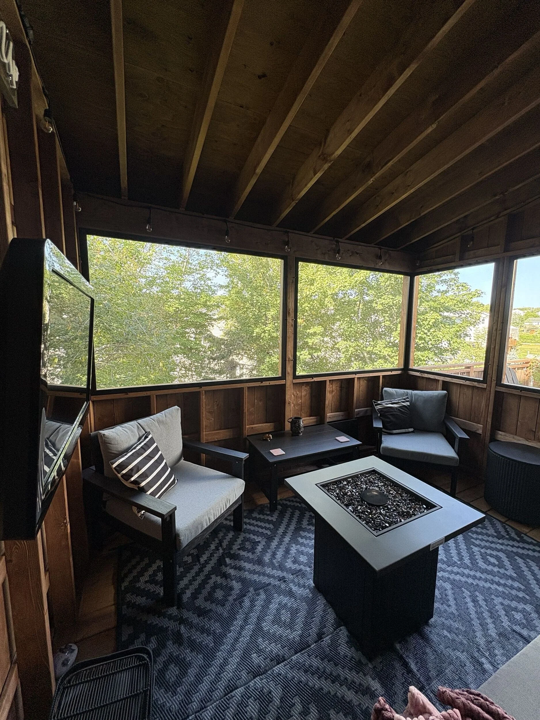 Interior of The Treehouse featuring natural wood finishes, screened openings, and comfortable seating for year-round outdoor living and entertaining.