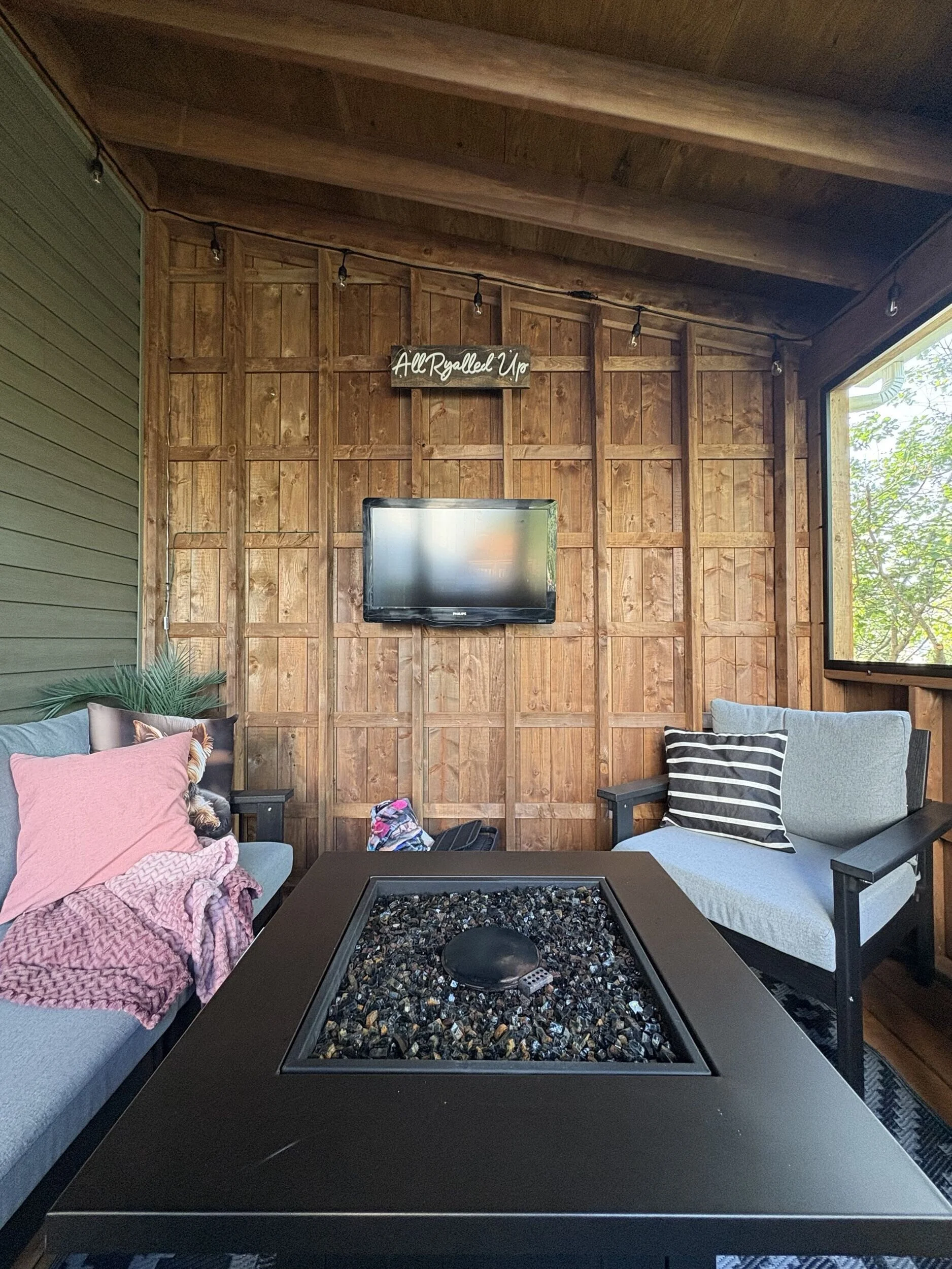 Interior of The Treehouse featuring natural wood finishes, screened openings, and comfortable seating for year-round outdoor living and entertaining.