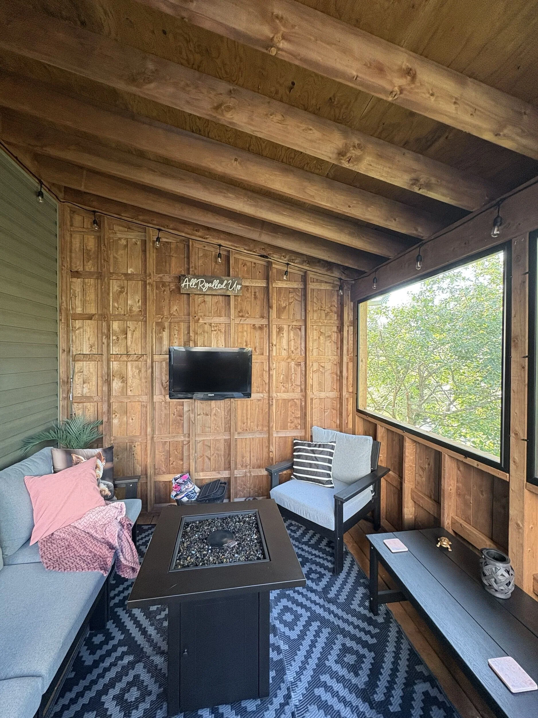Interior of The Treehouse featuring natural wood finishes, screened openings, and comfortable seating for year-round outdoor living and entertaining.