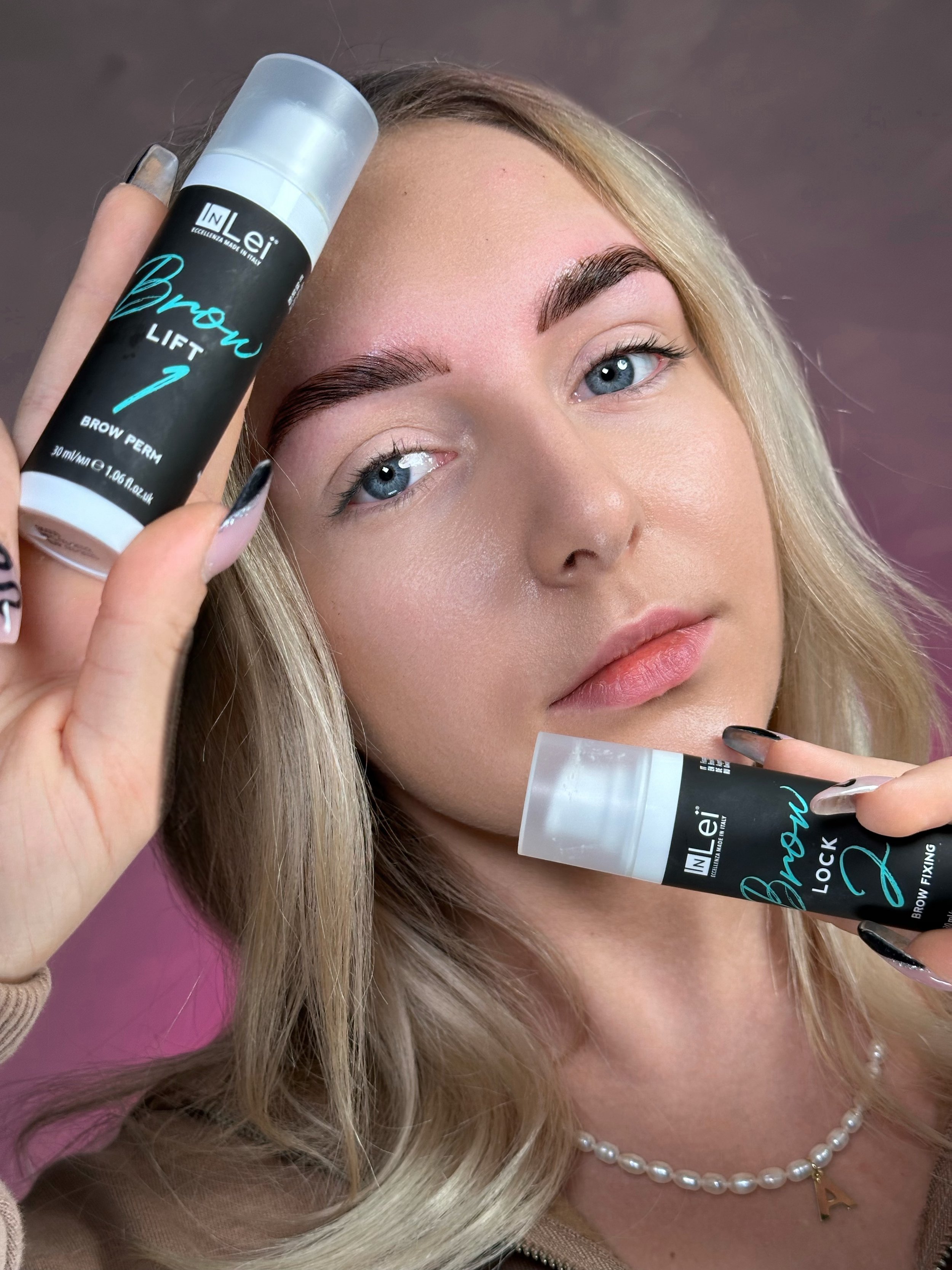 Person holding InLei brow lift and brow lock products with styled eyebrows.