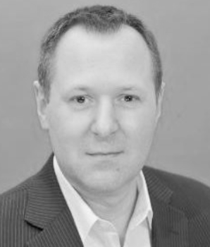 Black and white portrait of a man in a suit and white shirt, looking directly at the camera.