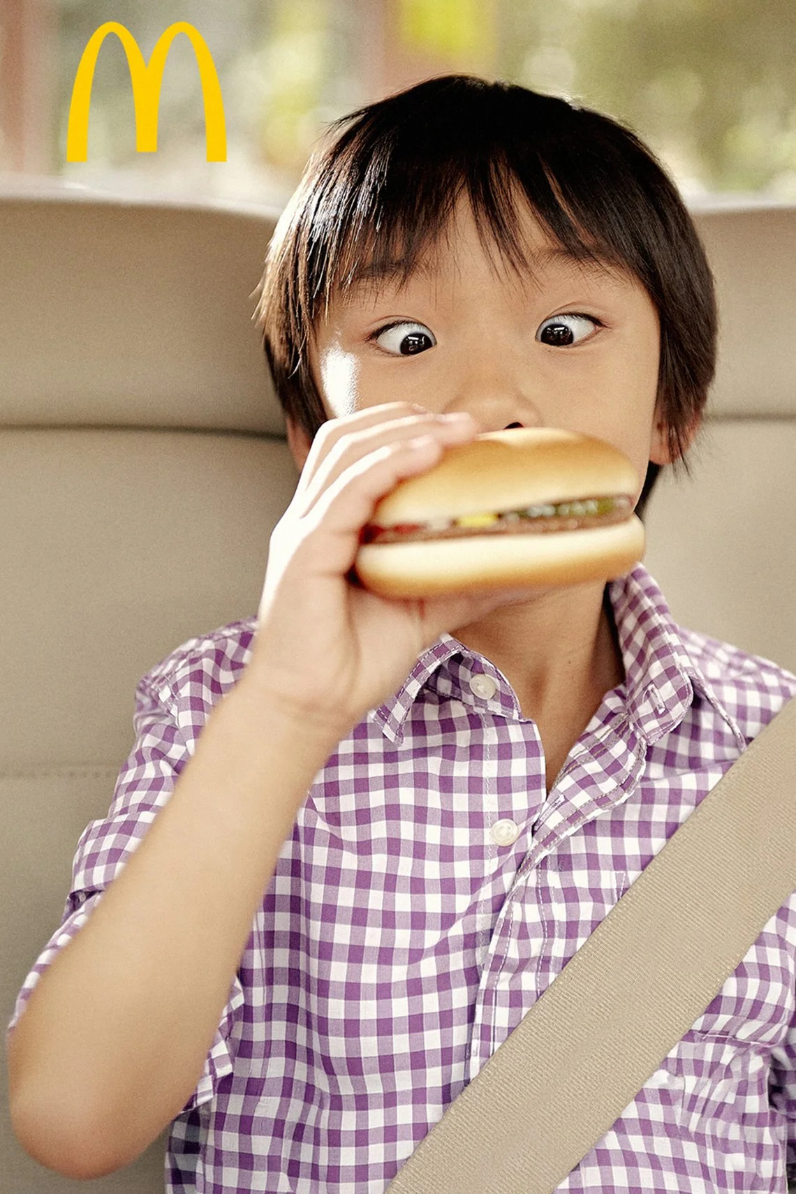 little boy holding a hamburger in the backseat of a car