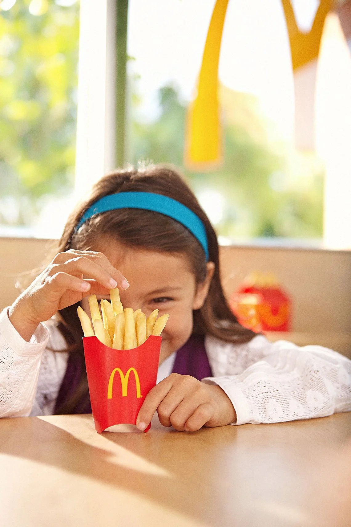 Little girl holding a small container of french fries 