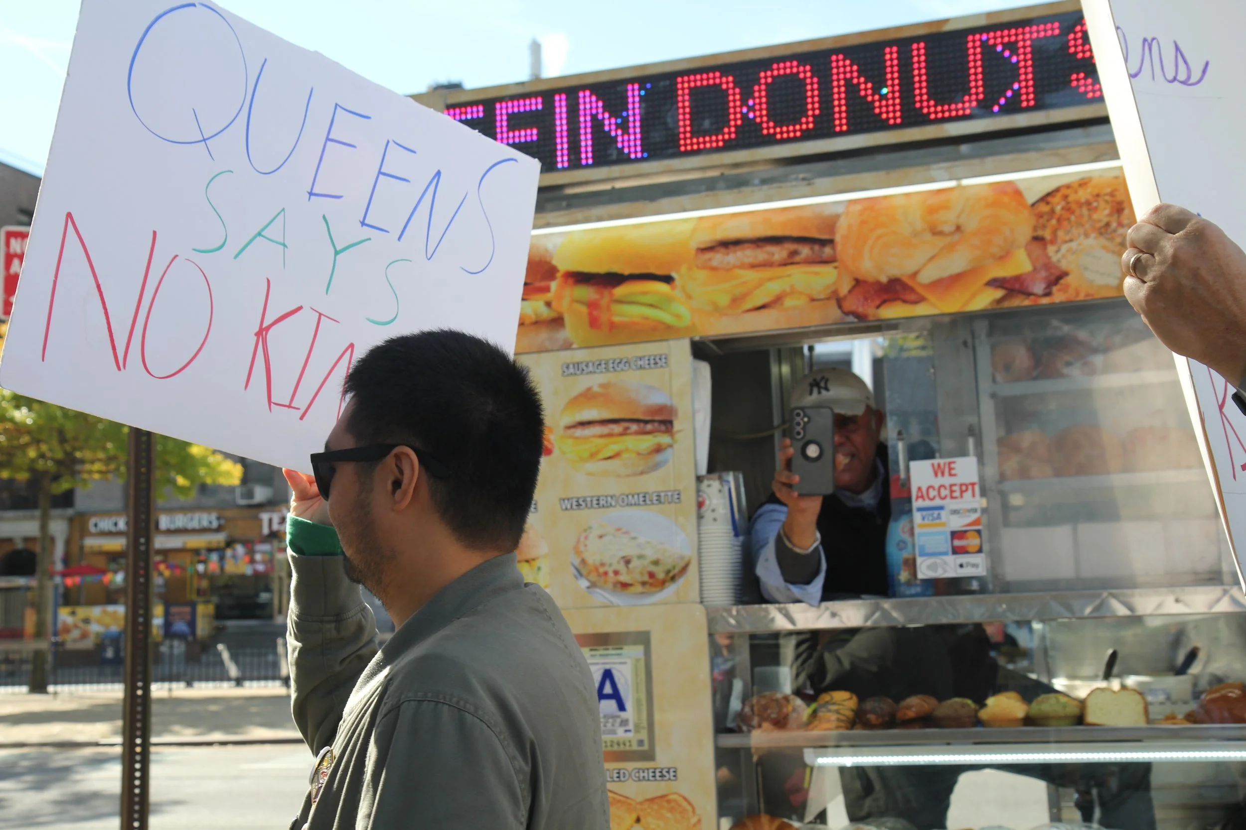 A vendor photographs protestors as they walk by his cart. October 2025.