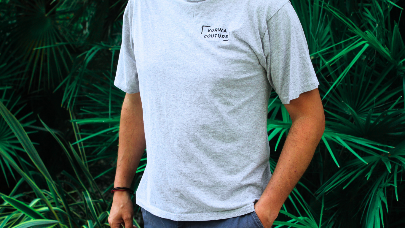 Man posing with a Kurwa Couture T-shirt with a green background