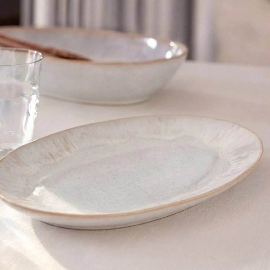 Close-up of a large, empty white ceramic bowl on a table set for dining.