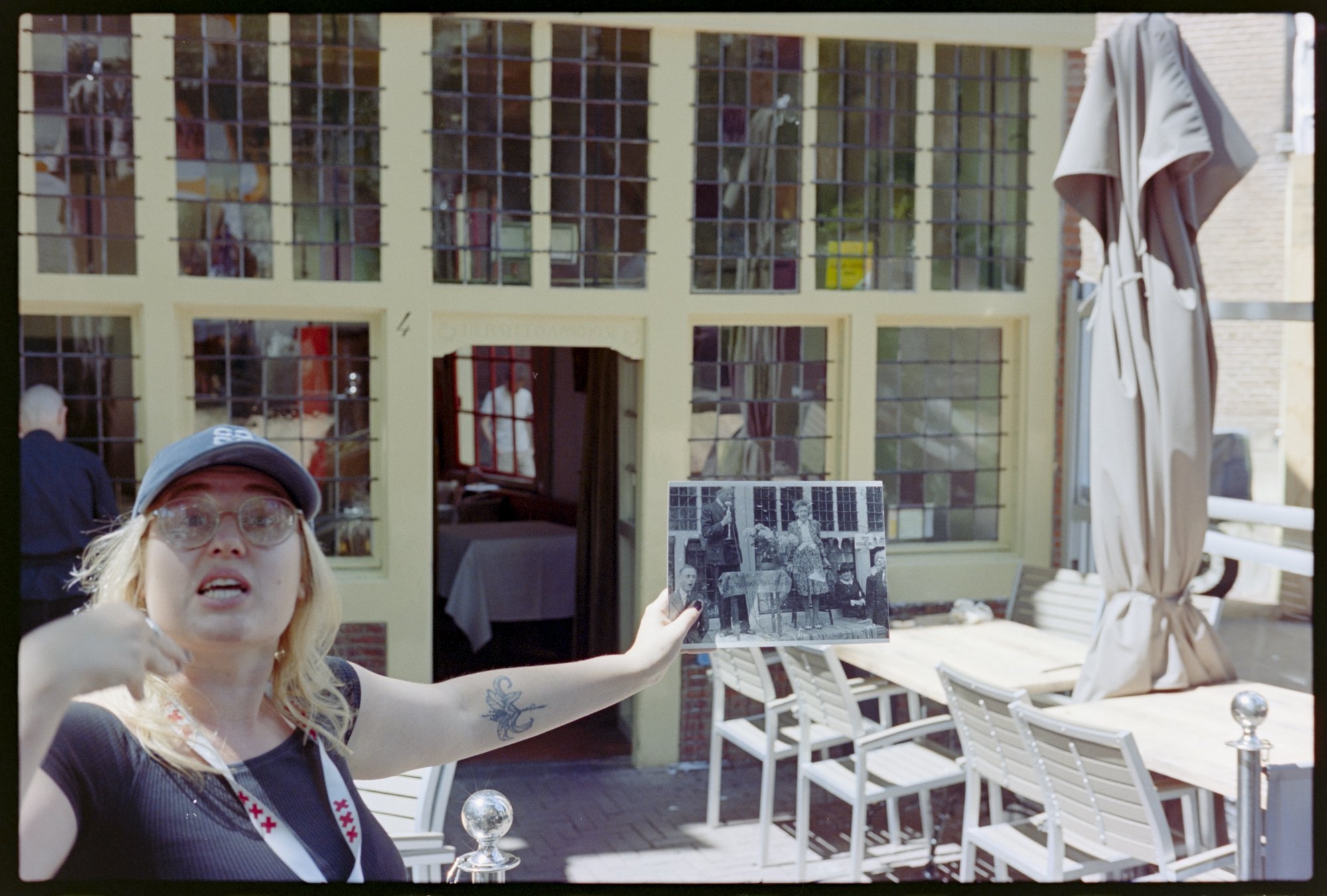An Amsterdam walking tour guide shows a photo of a restaurant in front of that restaurant depicting the owner during the war that hid a family of 16 receiving an award from the mayor.