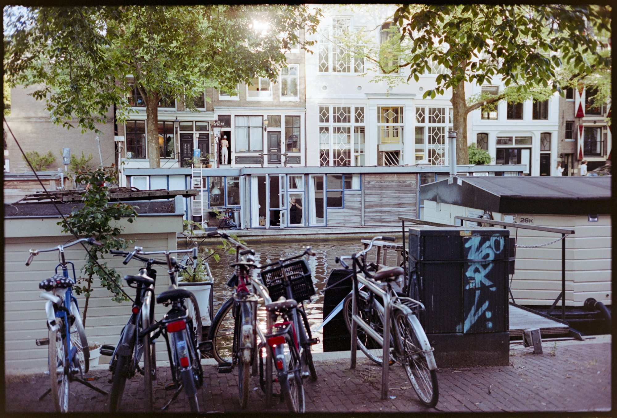 I love the layers in this shot. The bikes in front, the woman in her houseboat window in the middle, and a man working in the doorway of a building in the back, in Amsterdam.
