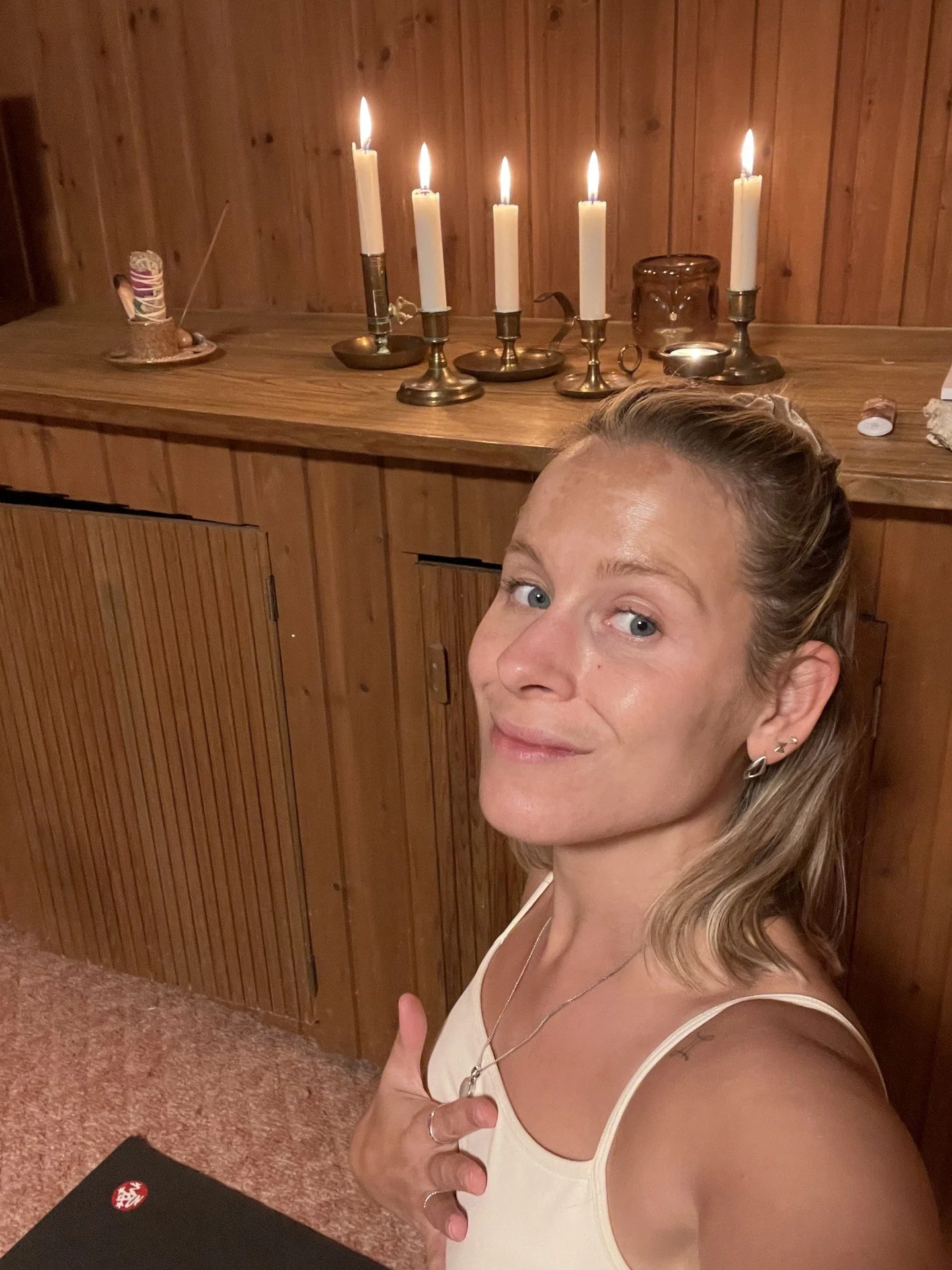 En kvinna tar en selfie i ett rum med träpanel på väggarna, framför henne finns en svart låda med en röd och vit emblem.