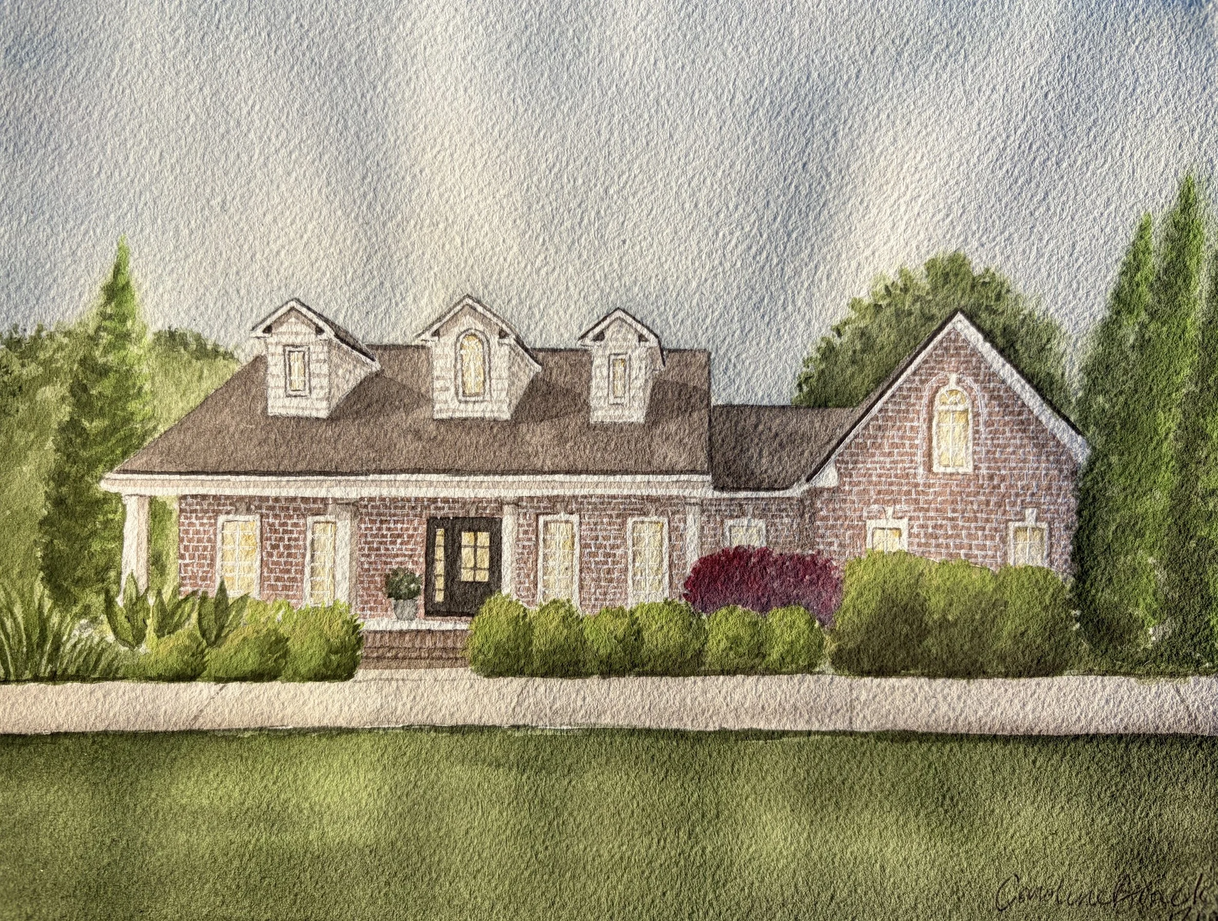 Watercolor painting of a brick house with a dark roof, multiple windows with yellow lights, surrounded by green trees and bushes, under a cloudy sky.
