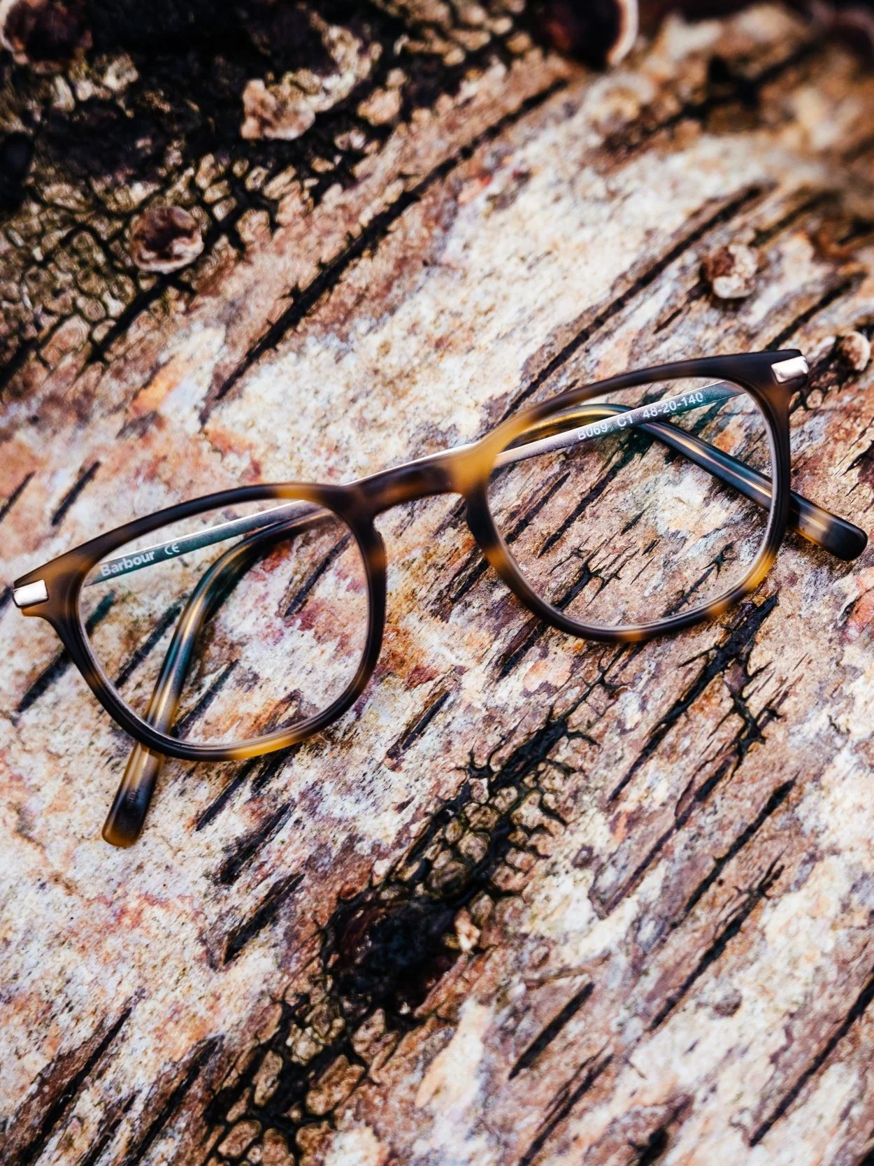 Eyeglasses with tortoiseshell frames placed on a textured wooden surface.