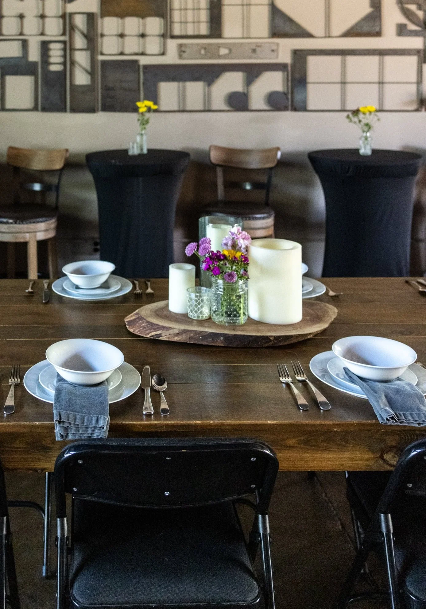 Dining table set with plates, bowls, candles, and floral centerpiece for a rehearsal dinner at The Garage in Bingen, WA