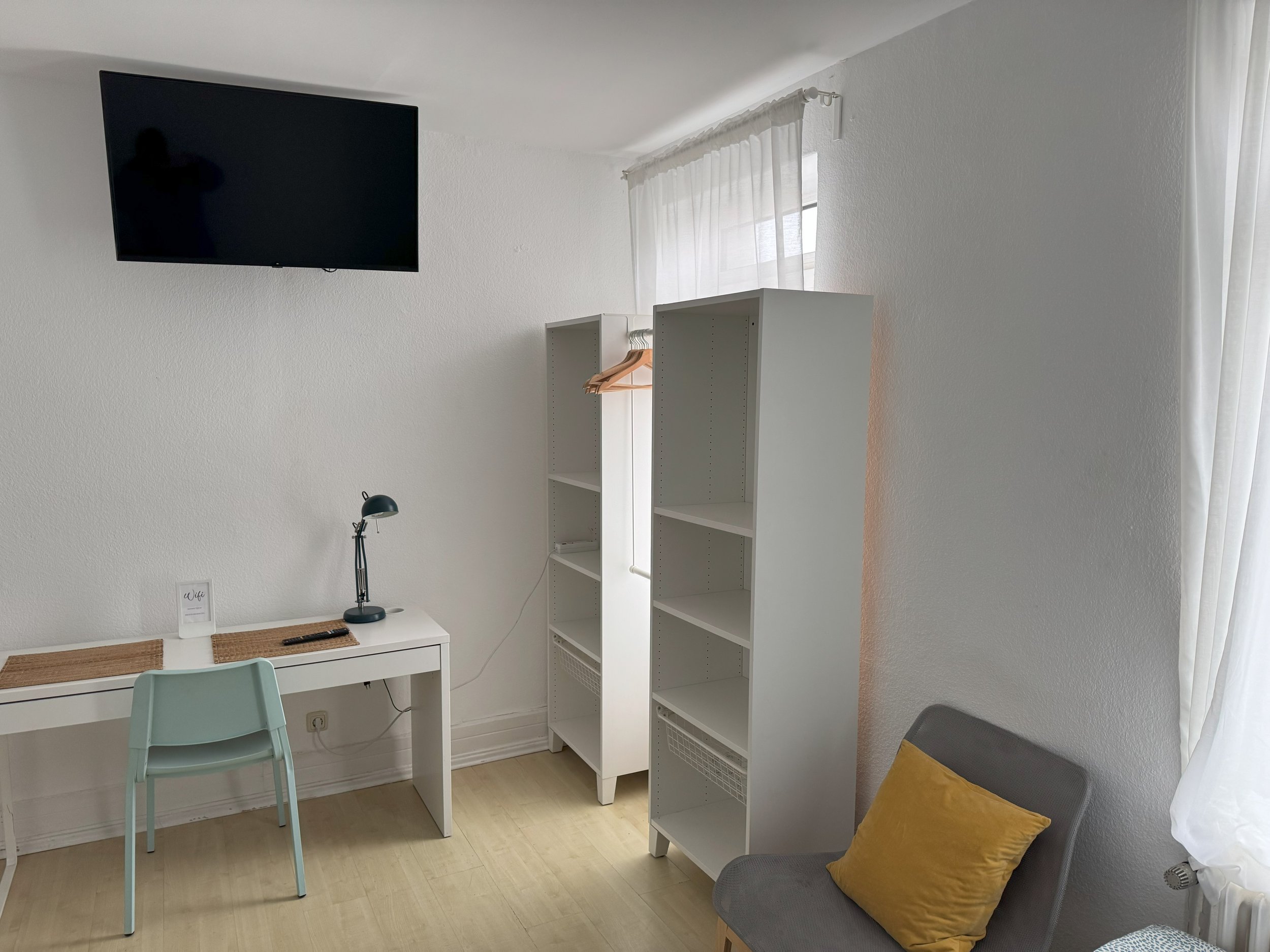Functional 1.5-room bedroom for long-term rental in Frankfurt with a work desk, two single beds, and natural light – perfect for business trips and work teams.
