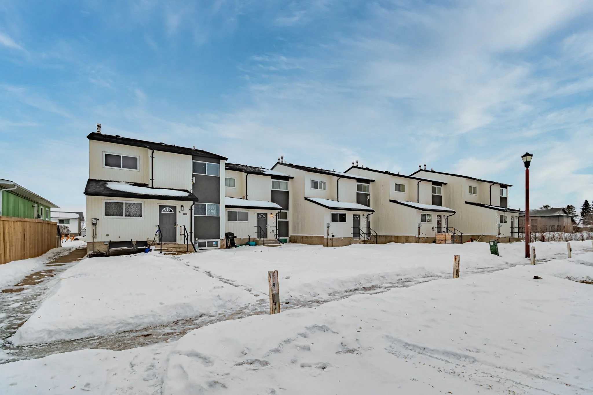 Row of townhouses with snow-covered ground and a clear blue sky.