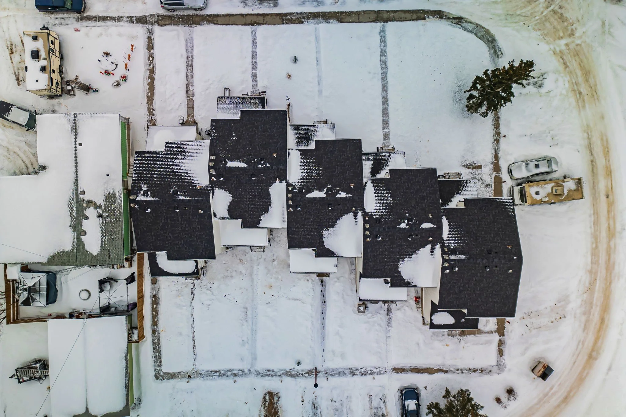 Aerial view of snow-covered houses and vehicles in a residential area