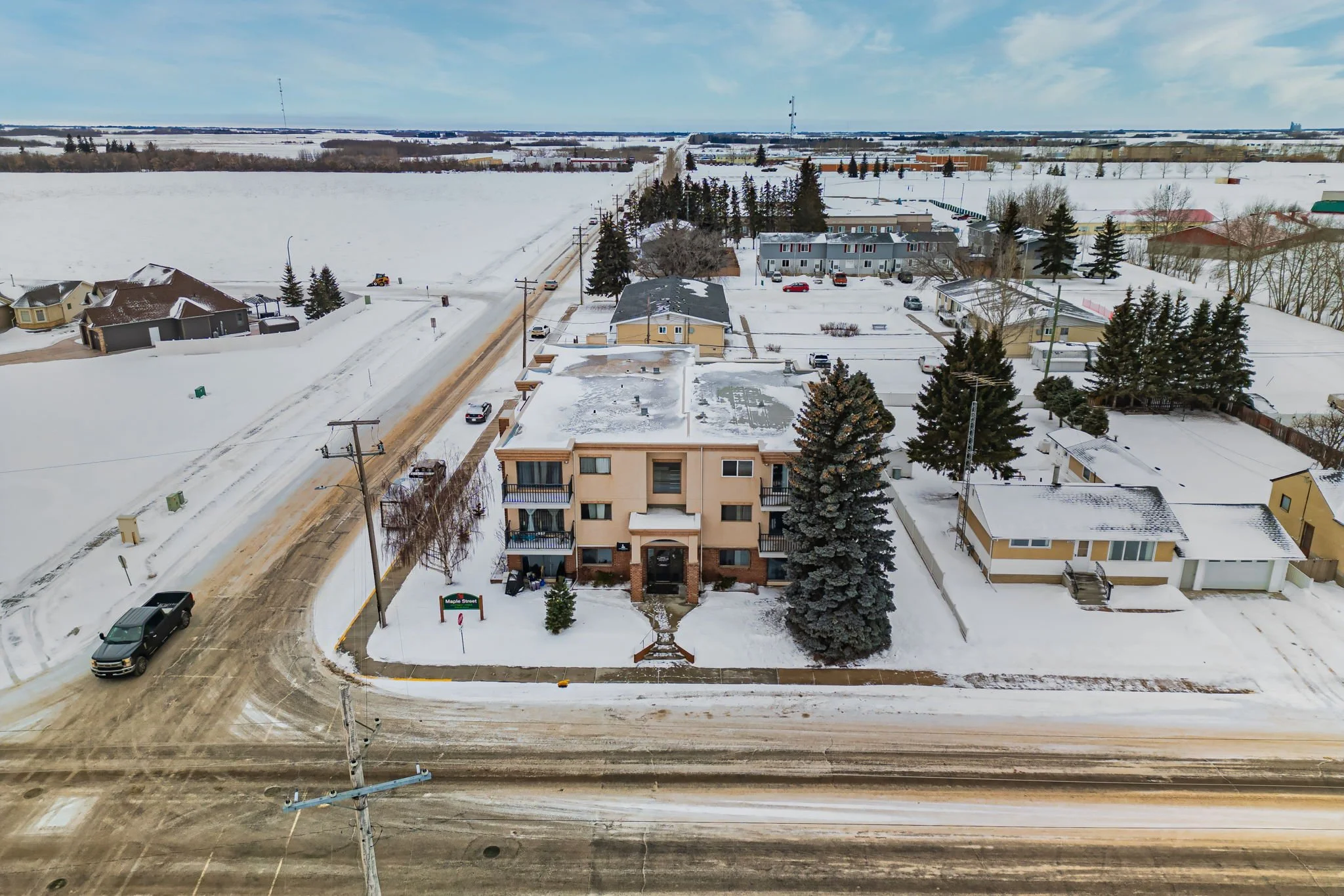 Aerial view of a snow-covered residential neighborhood with houses and roads in winter.