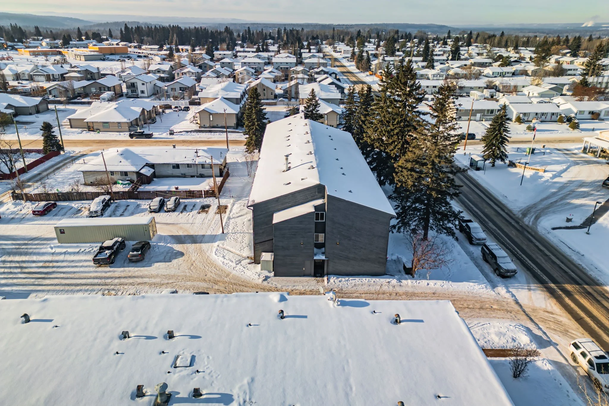 Snow-covered residential neighborhood with houses, trees, and streets during winter.
