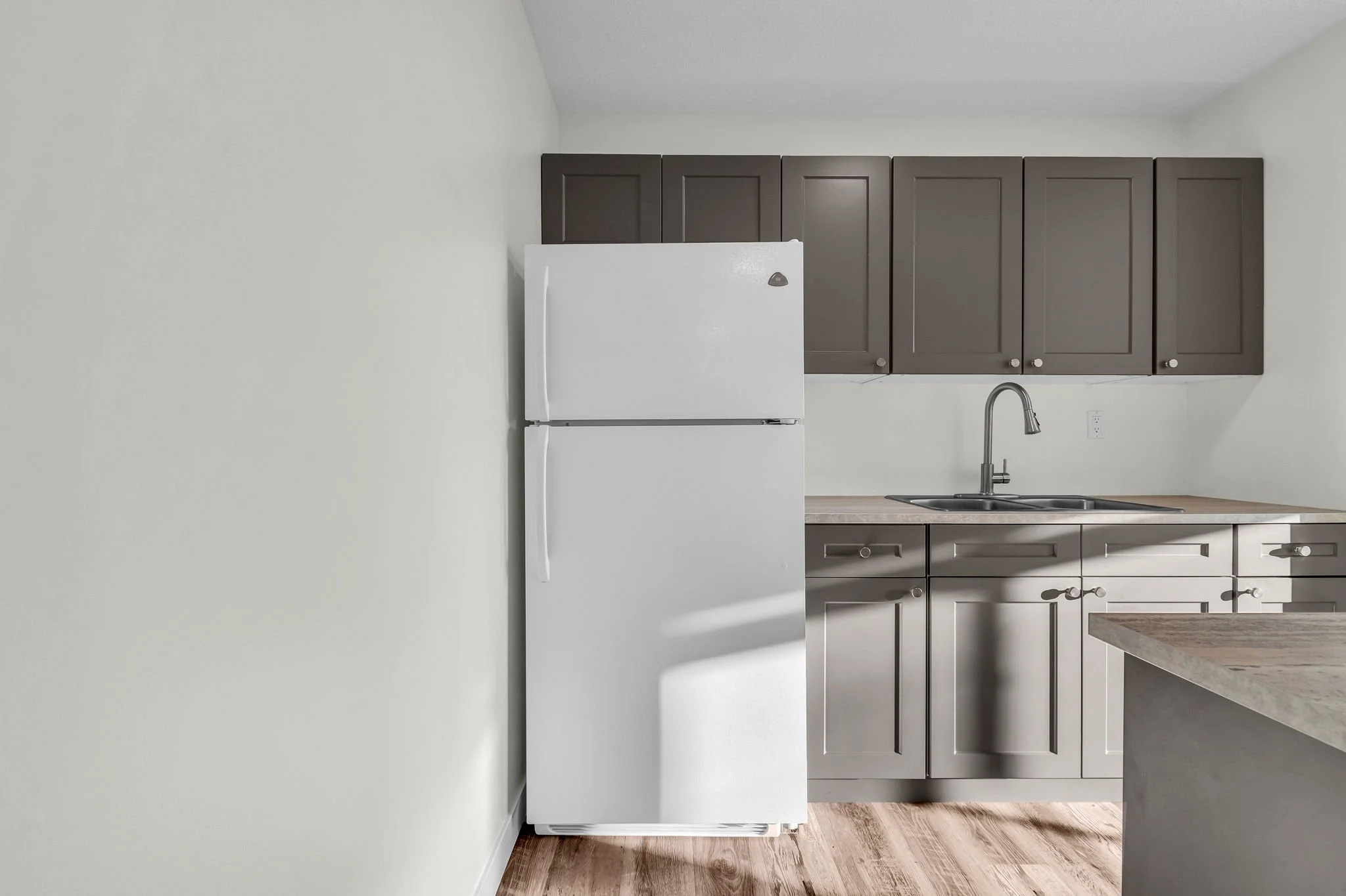 Modern kitchen with white refrigerator, gray cabinets, and wood flooring