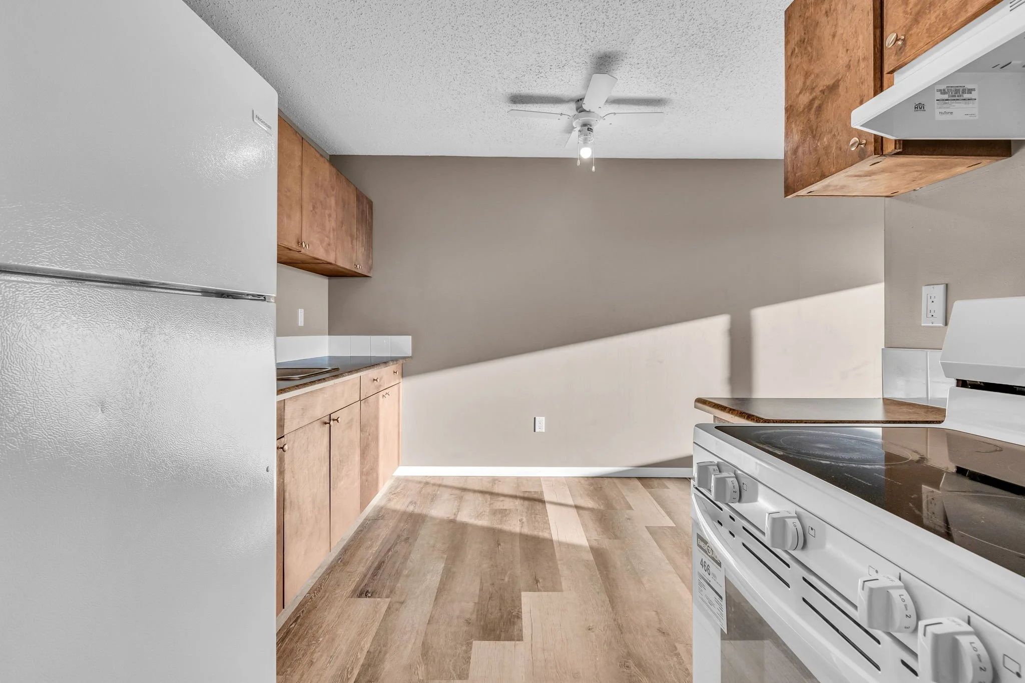 Small kitchen with white appliances, wooden cabinets, and hardwood flooring.